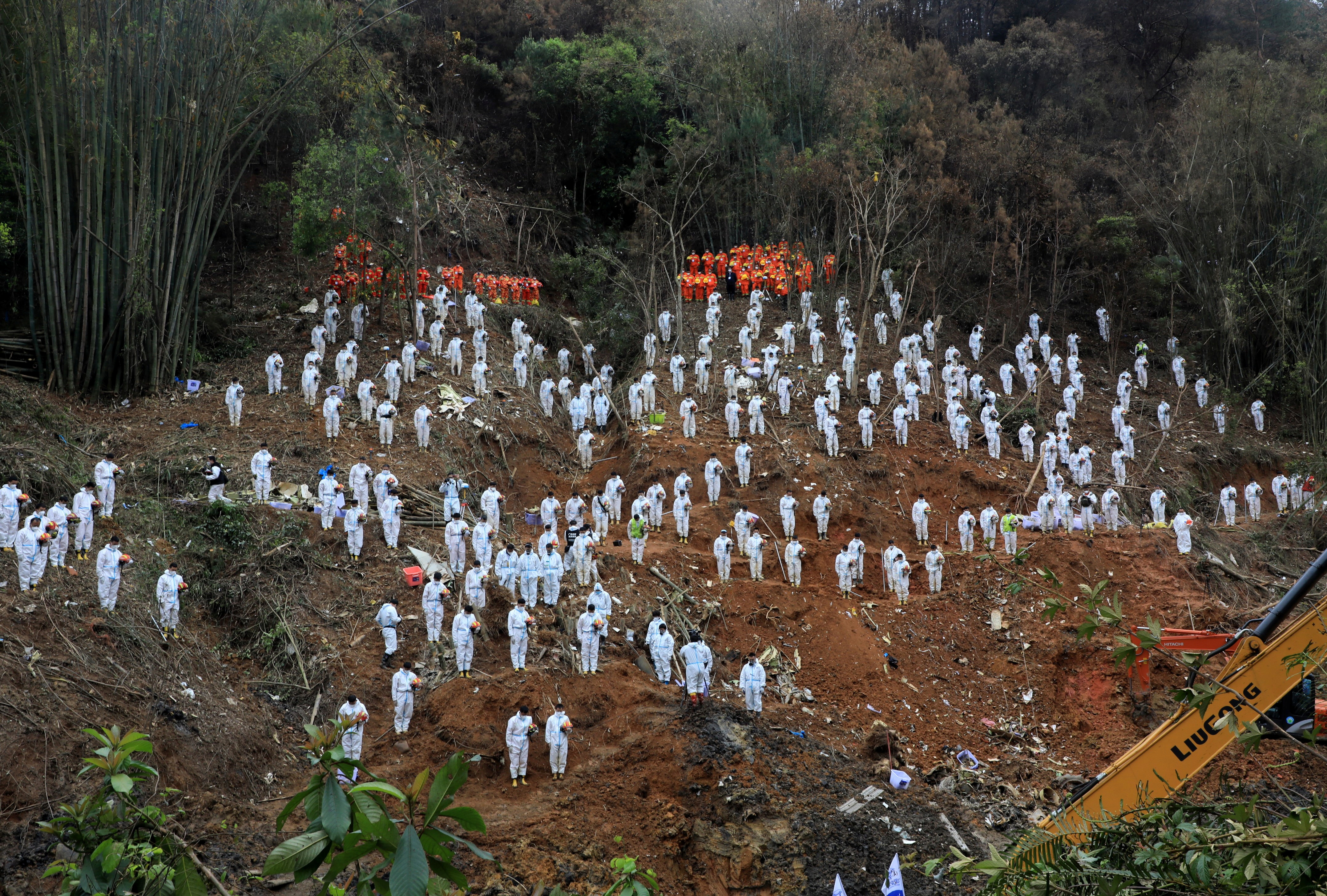 Rescue workers stand in a silent tribute to mourn plane crash victims in Wuzhou