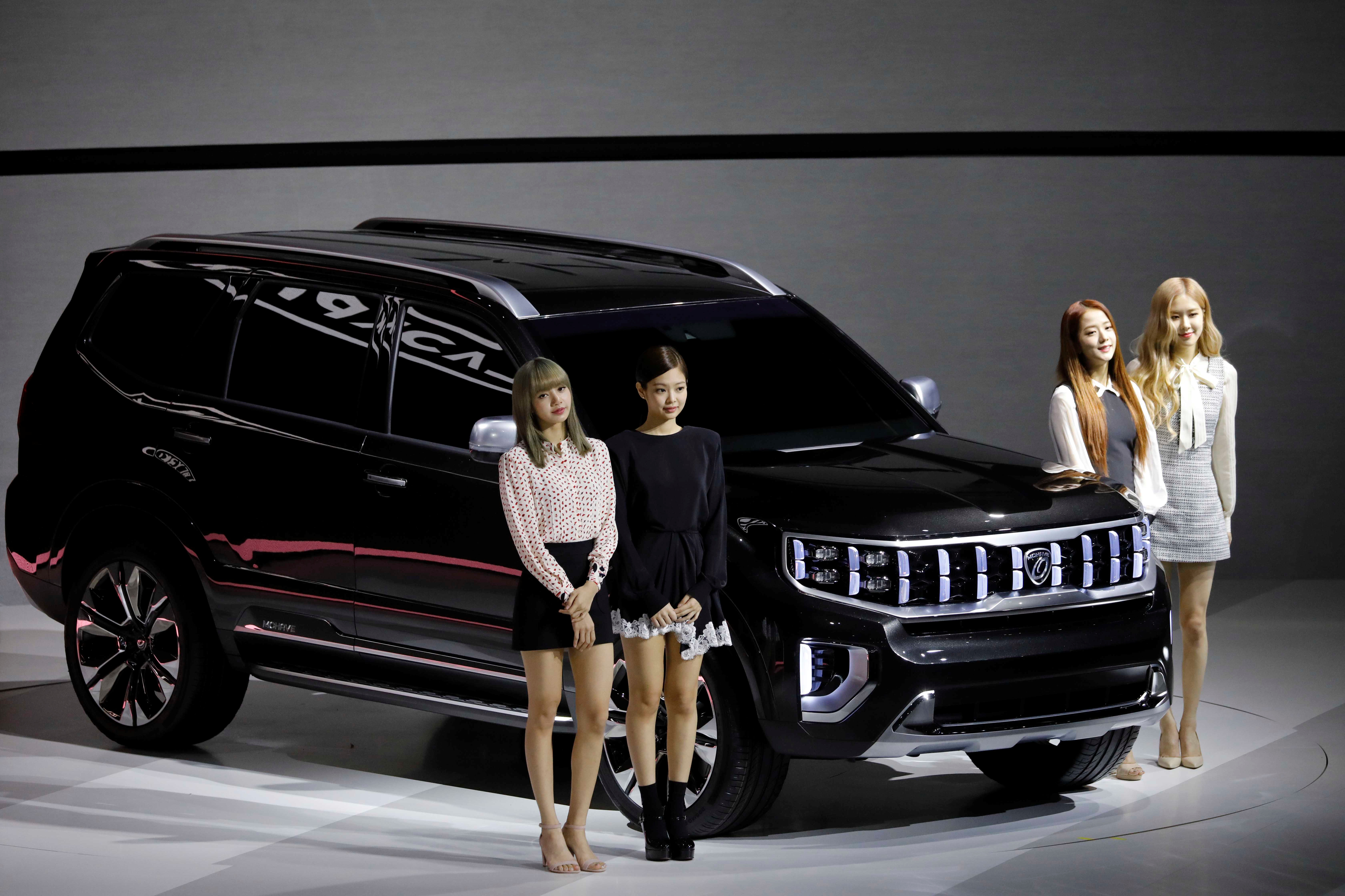 Members of K-pop idol group Black Pink pose for photographs with Kia Motors' Mohave during the 2019 Seoul Motor Show in Goyang