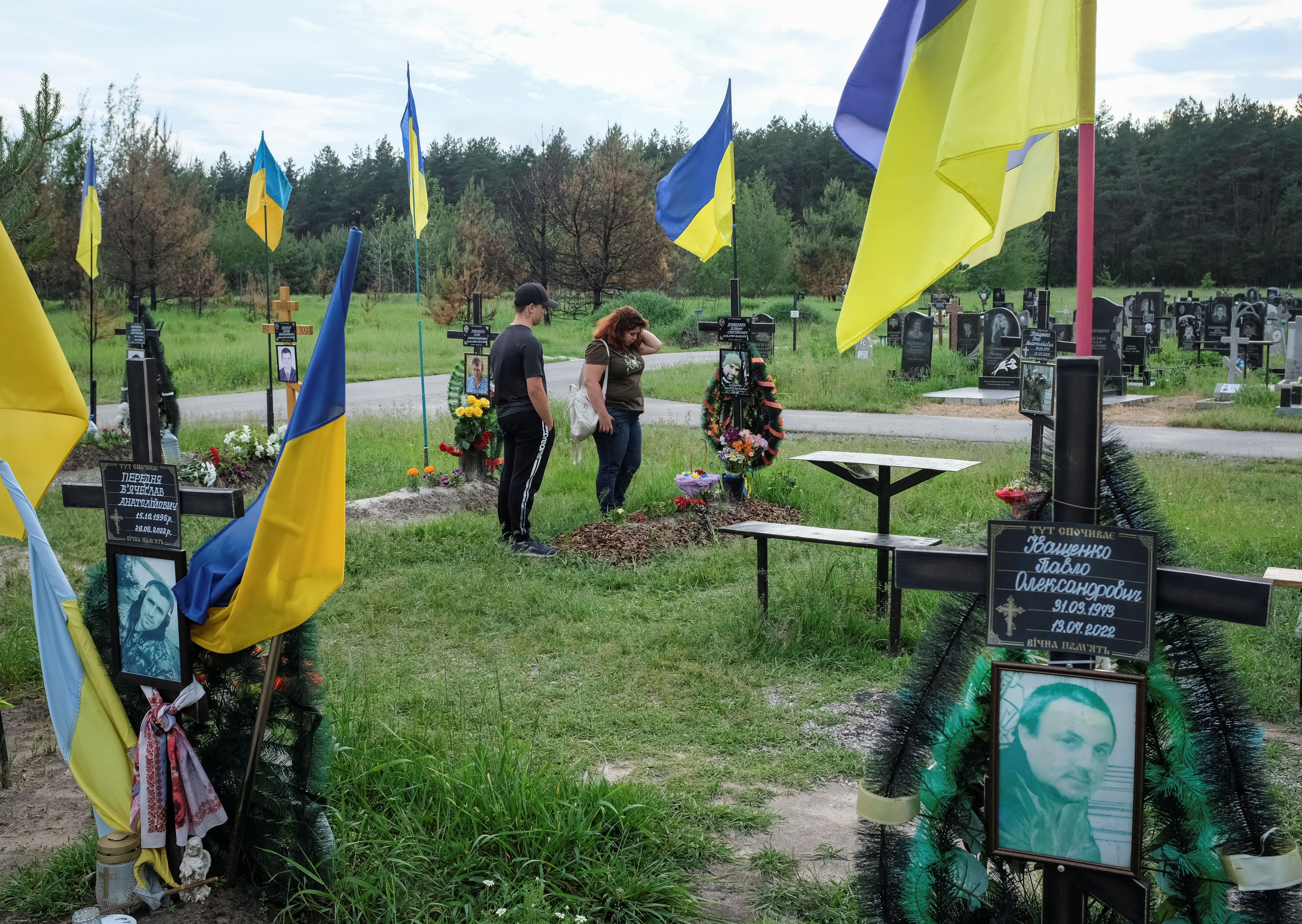 Tetiana Vatsenko-Bondareva reacts as she visits the grave of her husband Denys Bondarev at a cemetery in Poltava