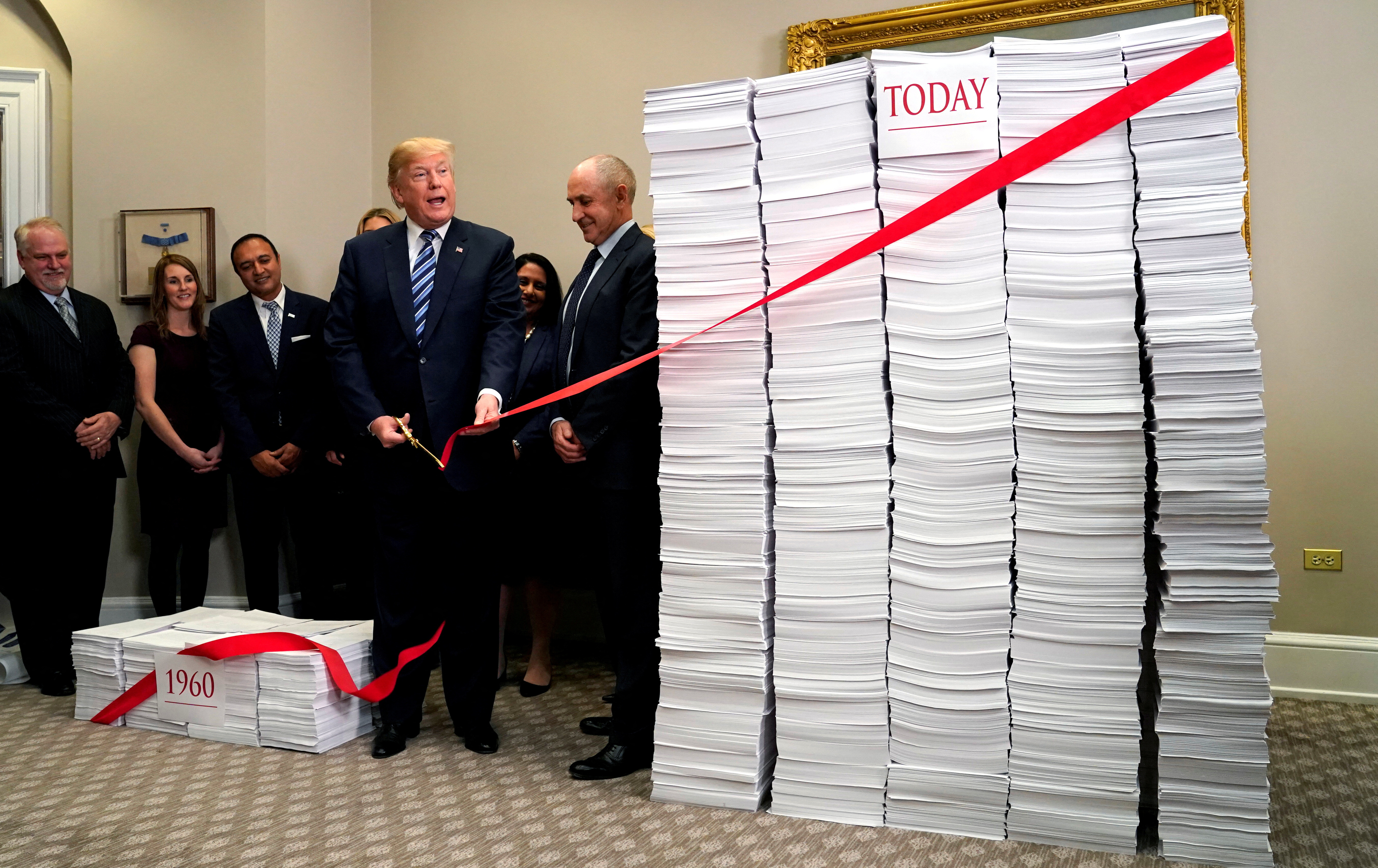 U.S. President Donald Trump cuts a red tape while speaking about deregulation at the White House in Washington