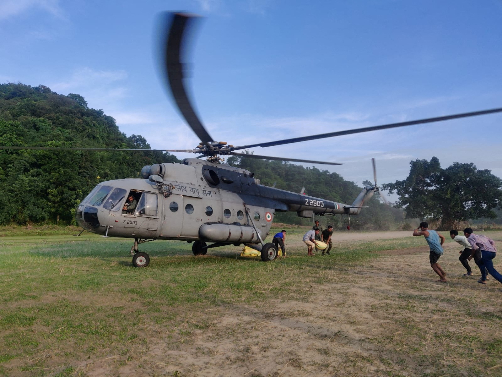 Men unload relief goods from an Indian Air Force helicopter to distribute it among the flood-affected people in the northeastern state of Meghalaya