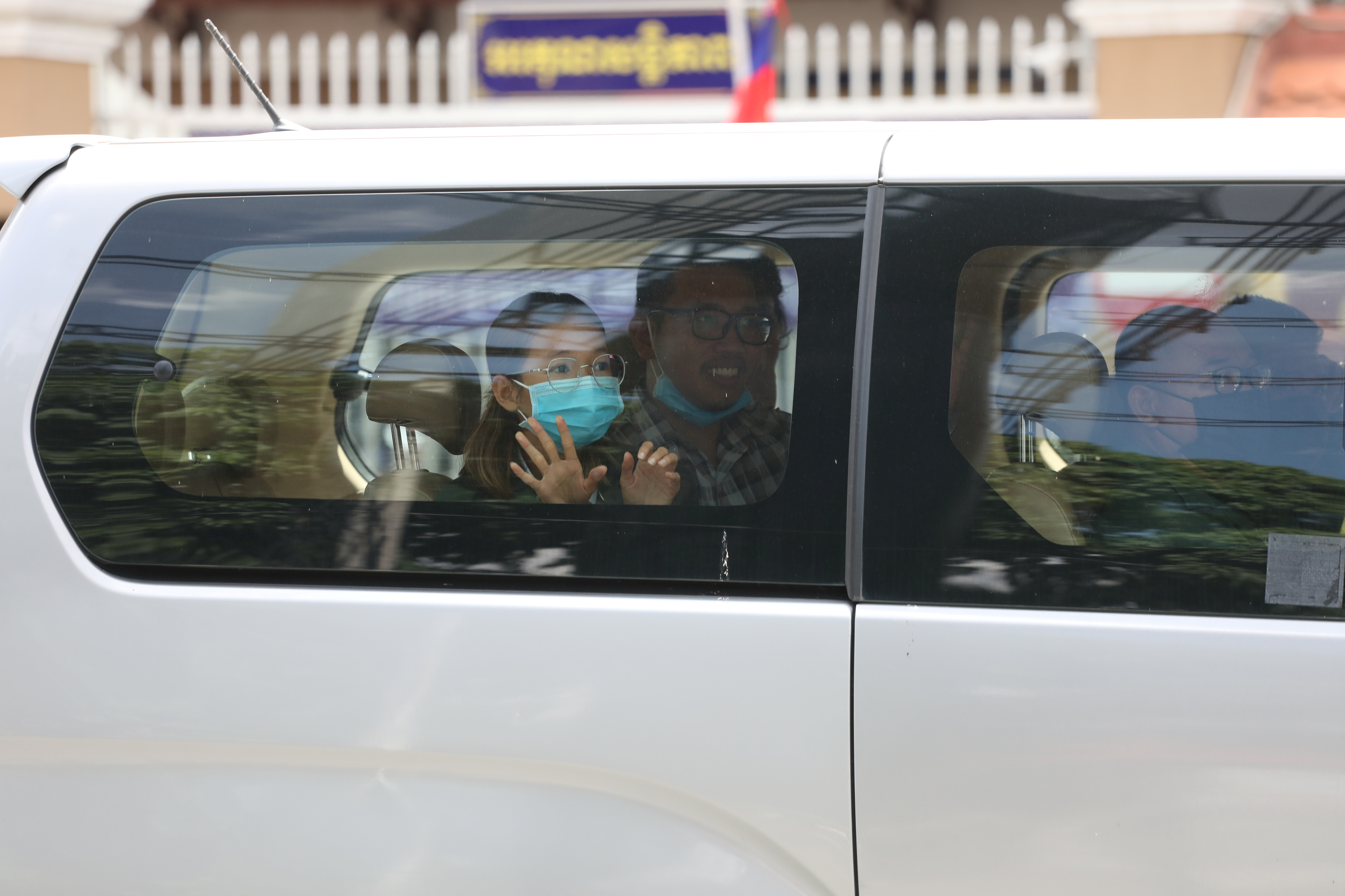 Detained members of the Mother Nature environmental group Sun Ratha and Yim Leanghy wave from a car after being charged with plotting and insulting the King, outside the court in Phnom Penh