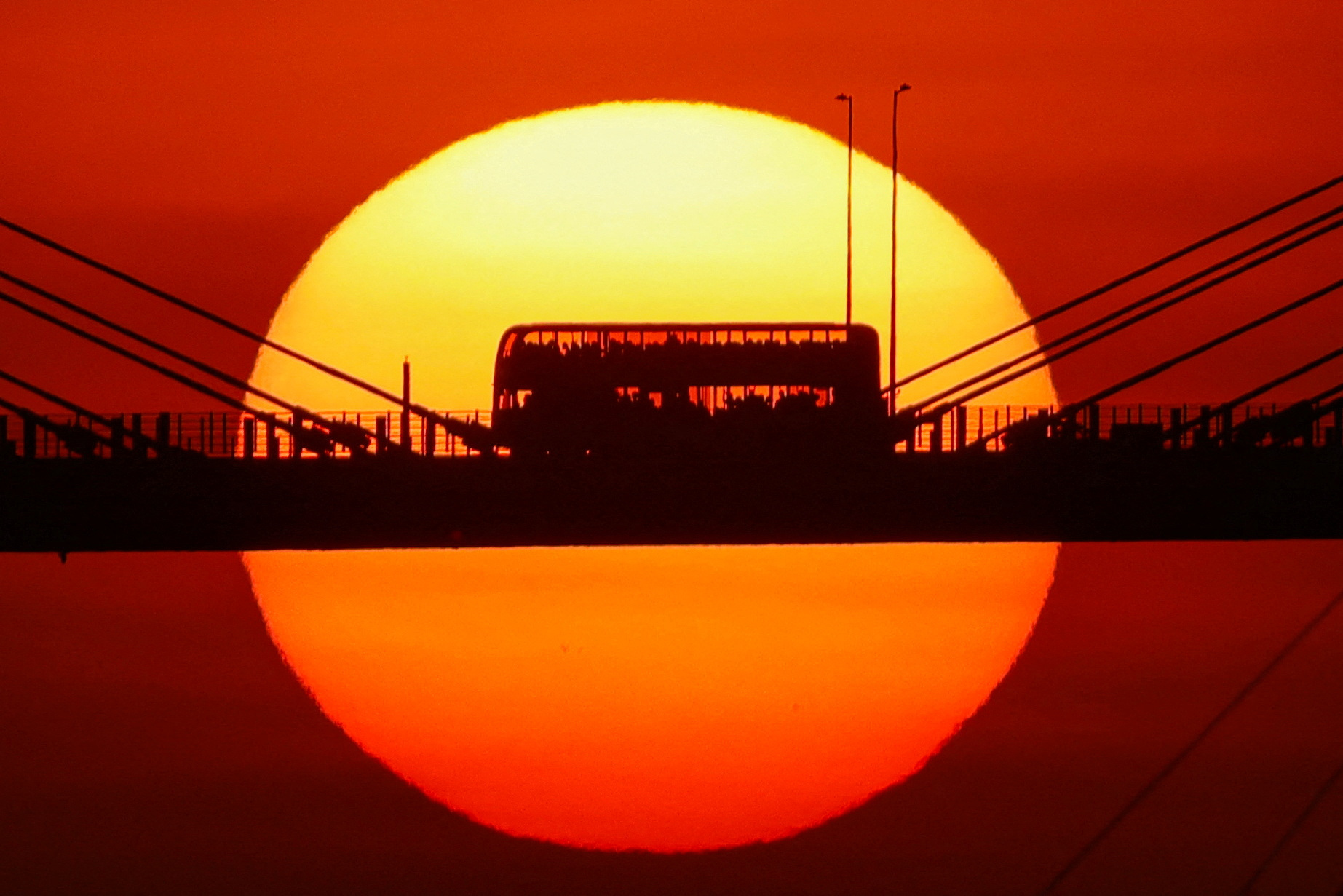 A double-decker bus passes through Ting Kau Bridge at sunset in Hong Kong