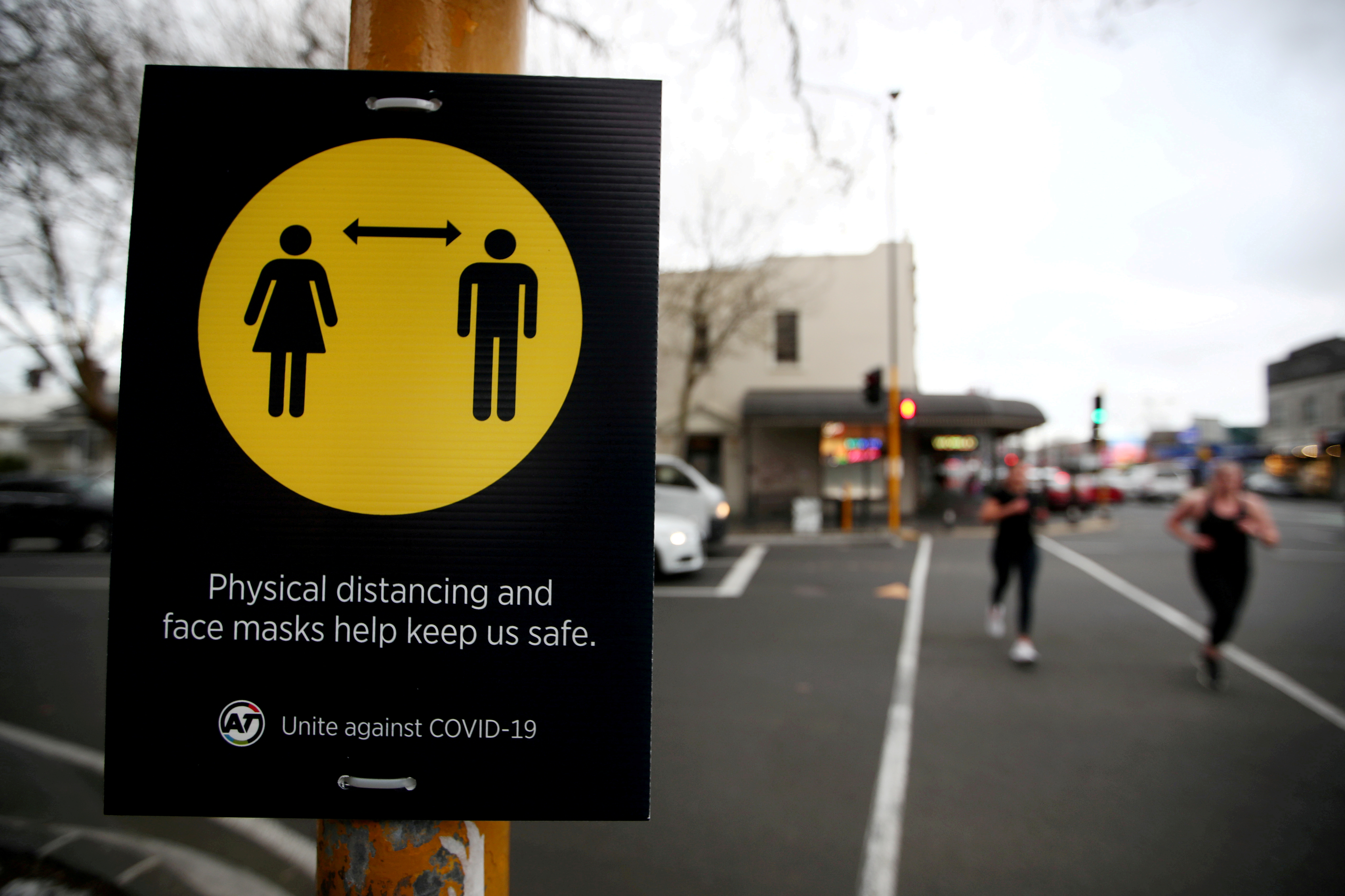 People jog past a social distancing sign in Auckland, New Zealand, August 31, 2020
