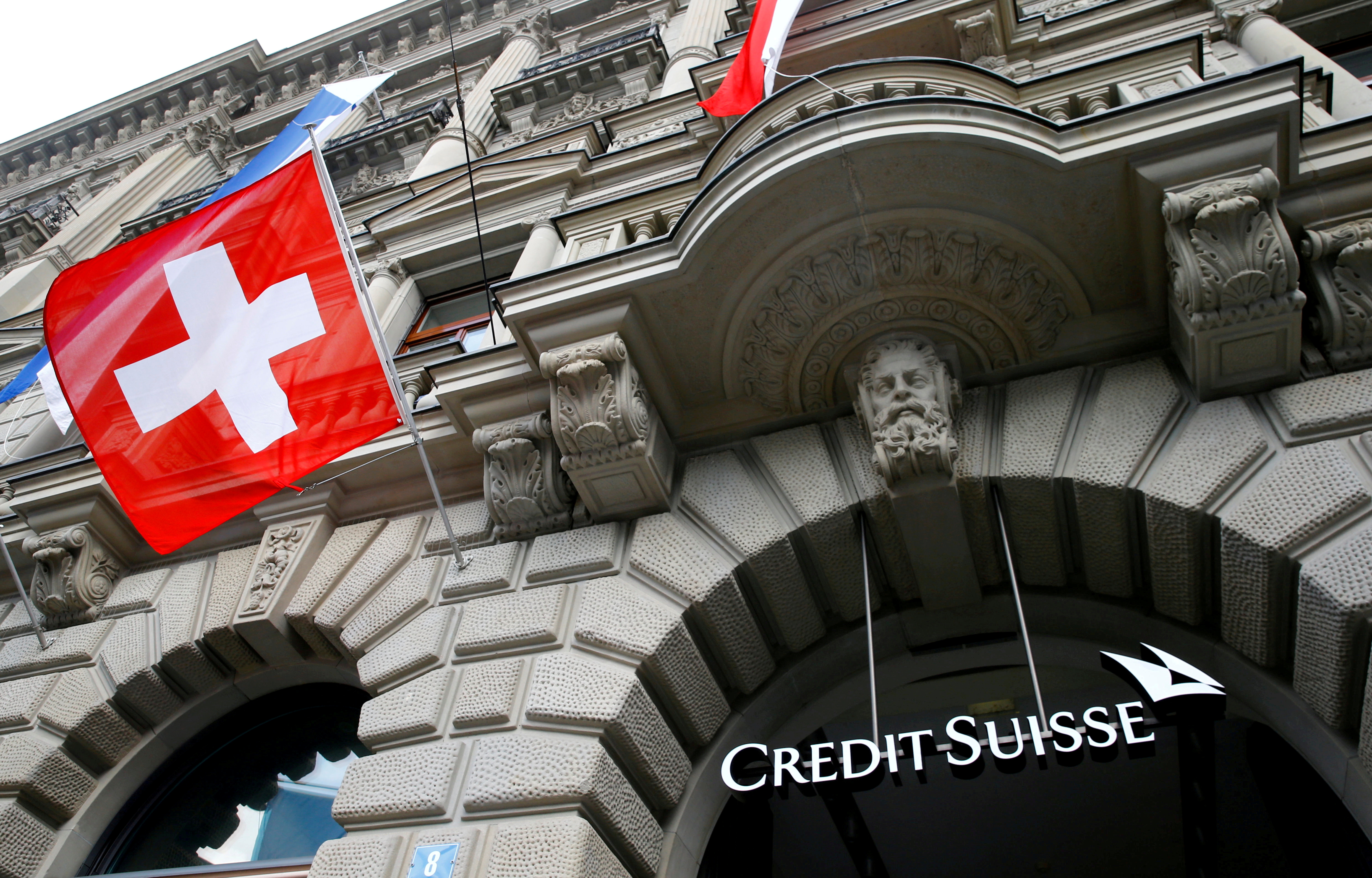 Switzerland's national flag flies below a logo of Swiss bank Credit Suisse in Zurich
