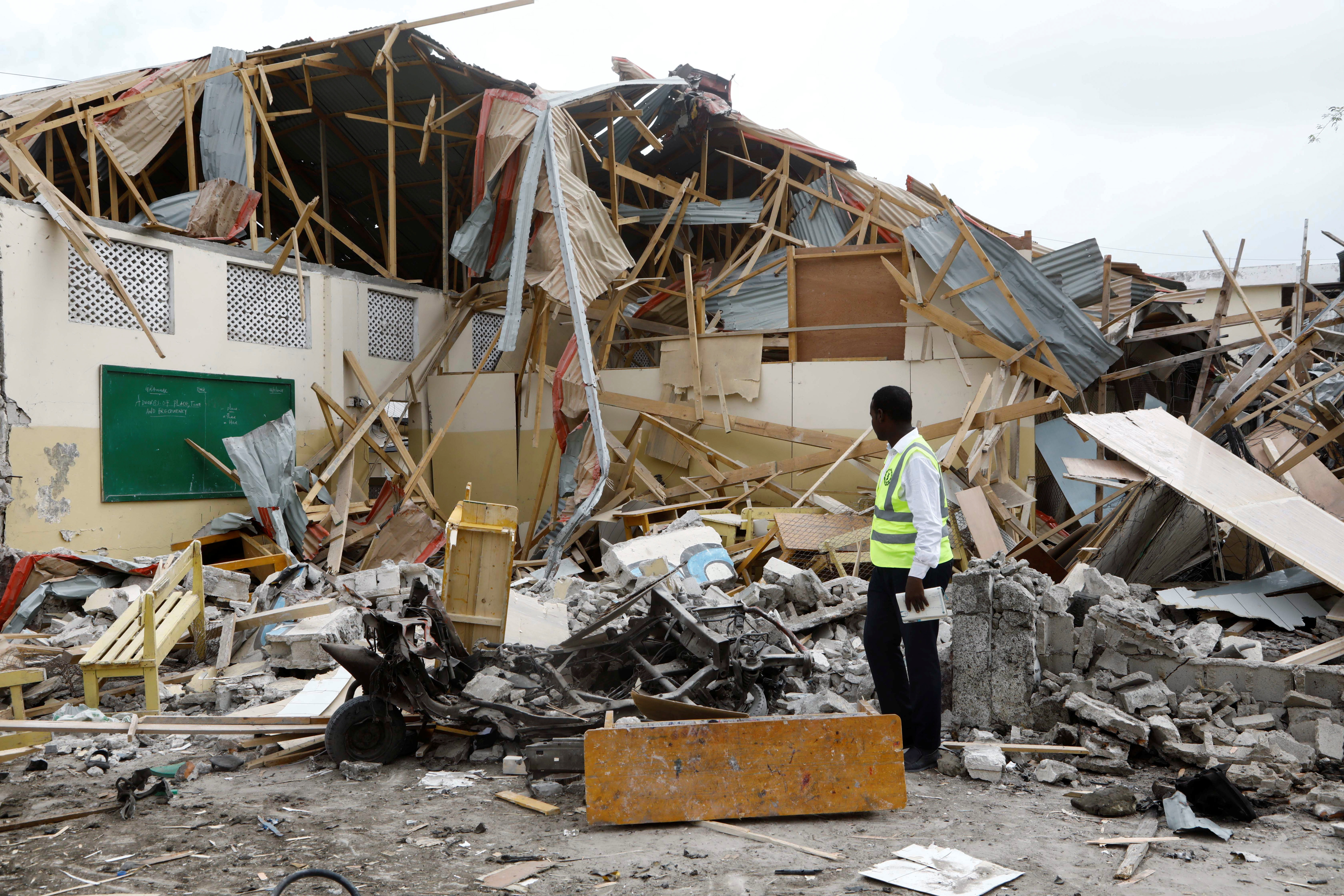 A policeman looks through the debris of a classroom after a car exploded in a suicide attack near Mucassar primary and secondary school in Hodan district of Mogadishu