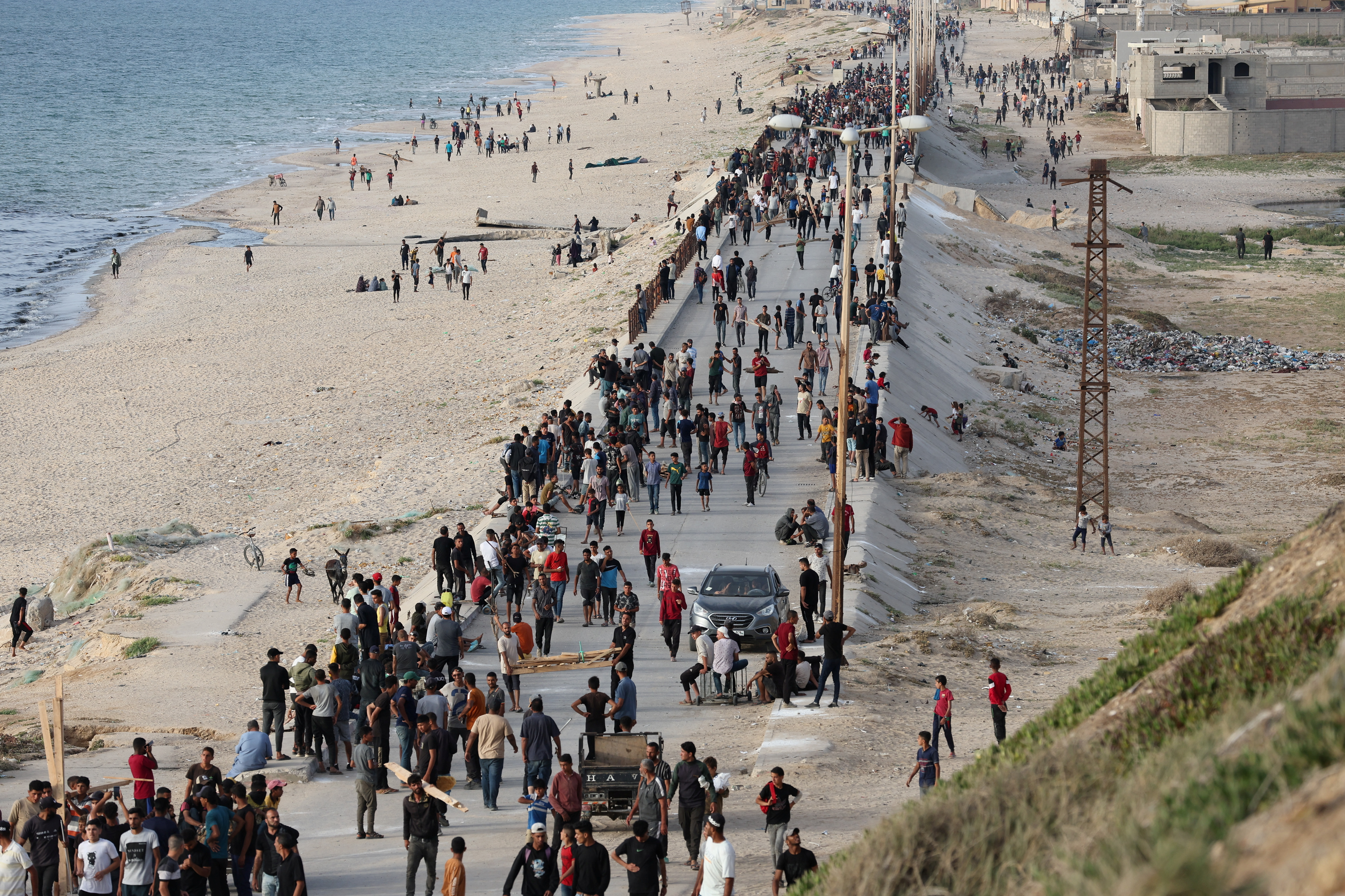 Palestinians gather in the hope of obtaining aid delivered into Gaza through a U.S.-built pier, as seen from central Gaza Strip