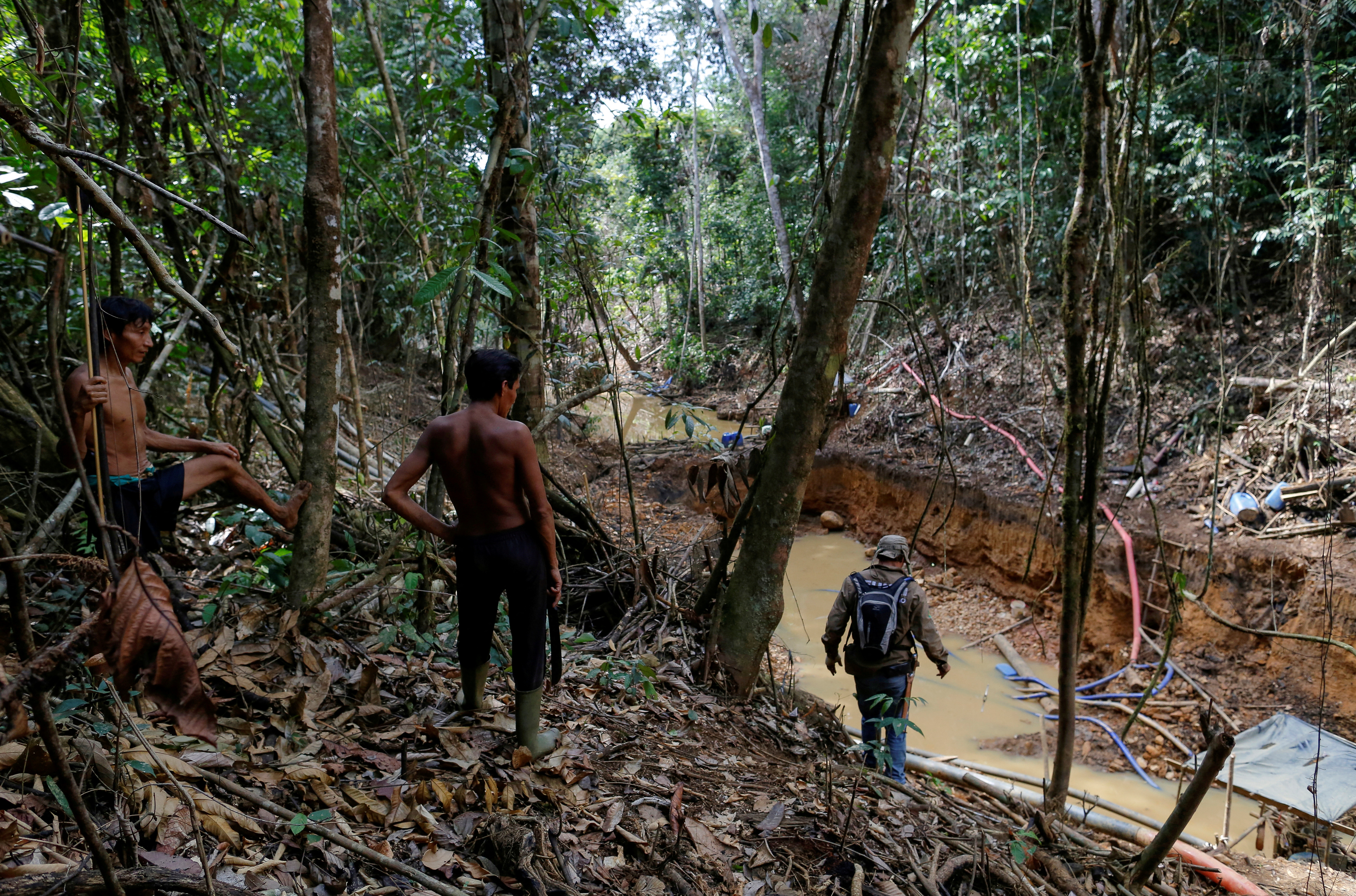 Yanomami indians follow agents of Brazil's environmental agency in a gold mine during an operation against illegal gold mining on indigenous land, in the heart of the Amazon rainforest