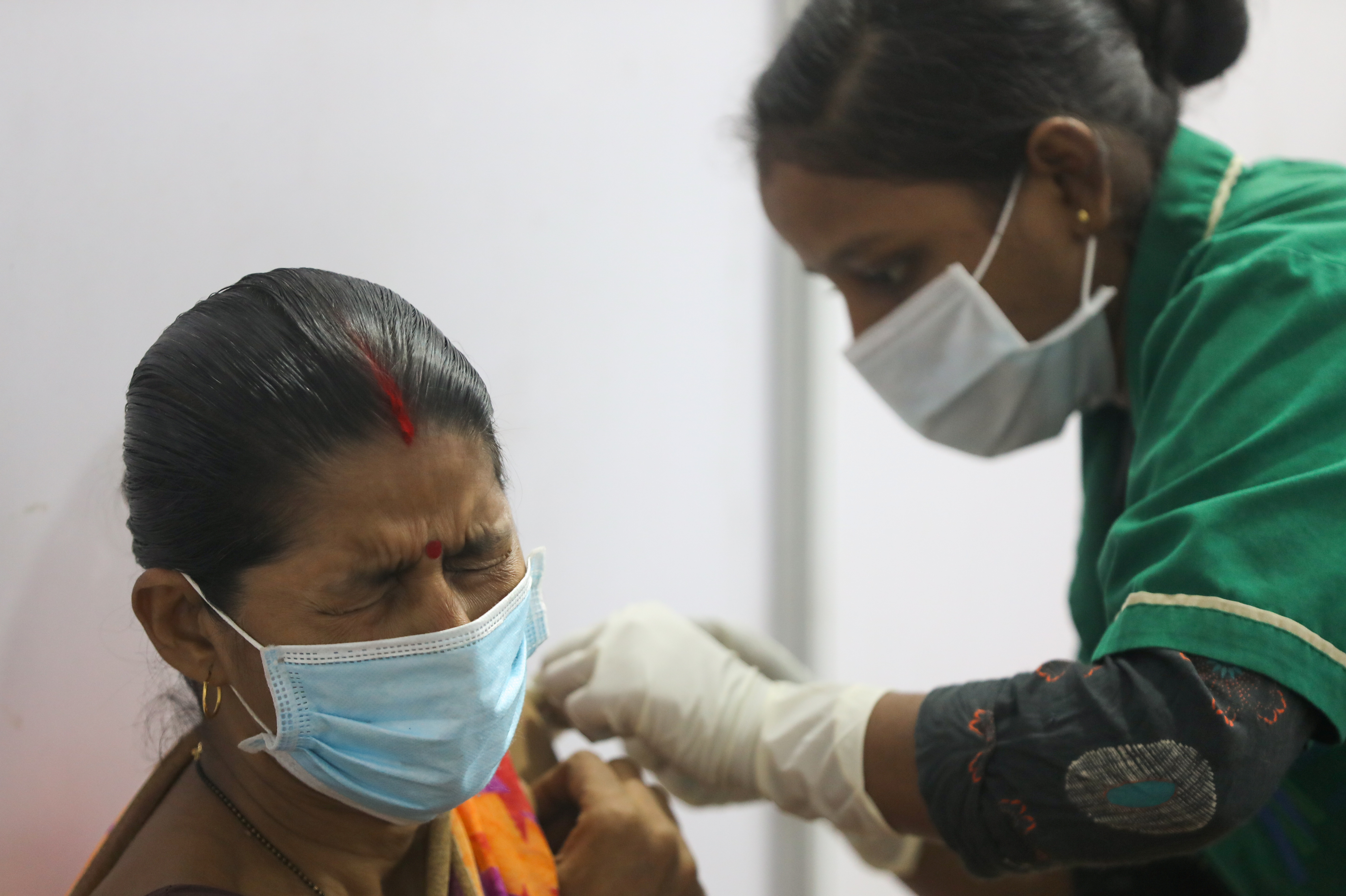 A woman reacts as she receives a dose of COVISHIELD, a COVID-19 vaccine manufactured by Serum Institute of India, in Mumbai