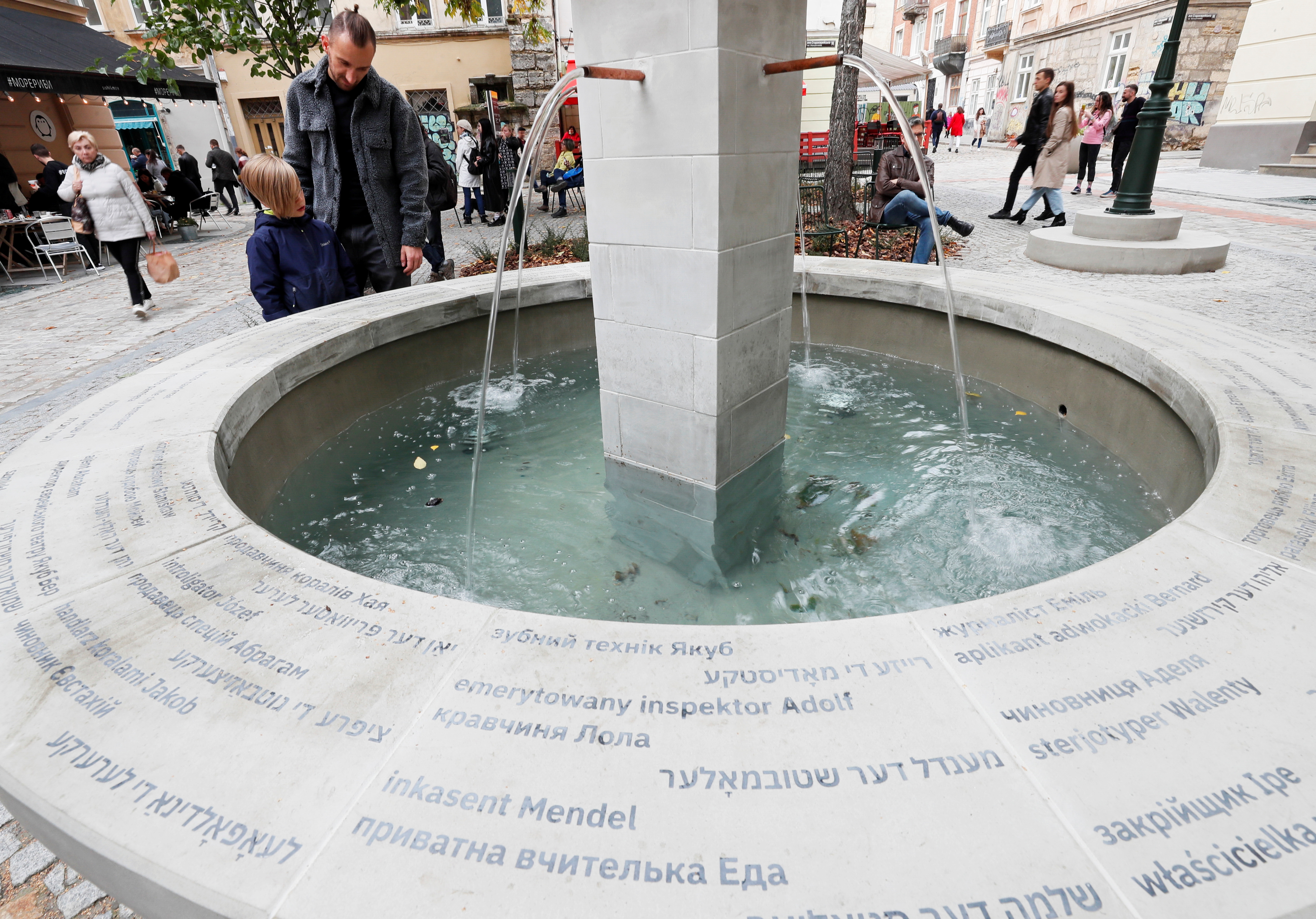 People stand by the fountain, which is engraved with the names of 70 Jews who lived in the area before World War Two, in Lviv