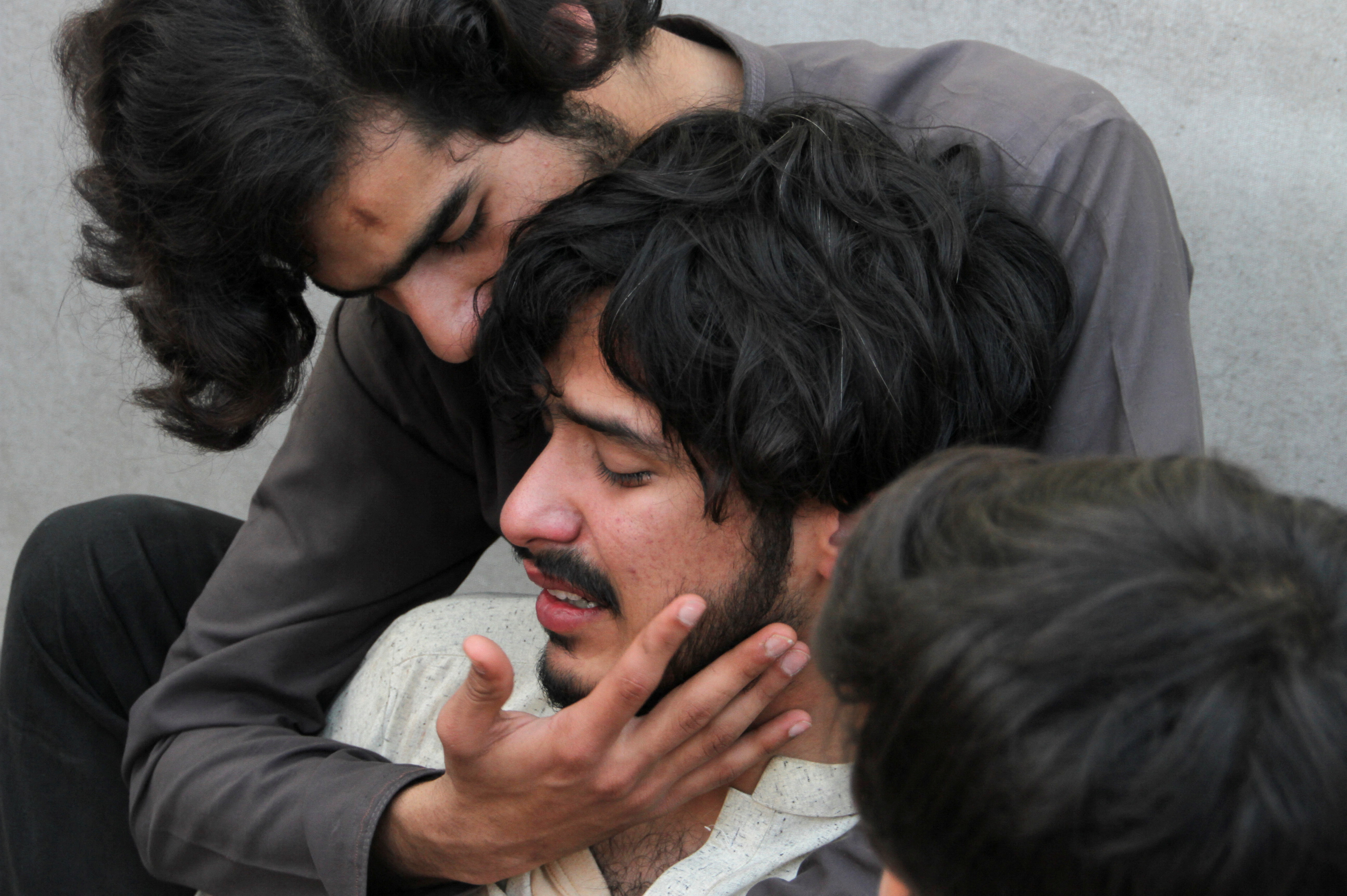 Relatives of the victims comfort each other, after a bomb blast in a mosque during Friday prayers in Peshawar