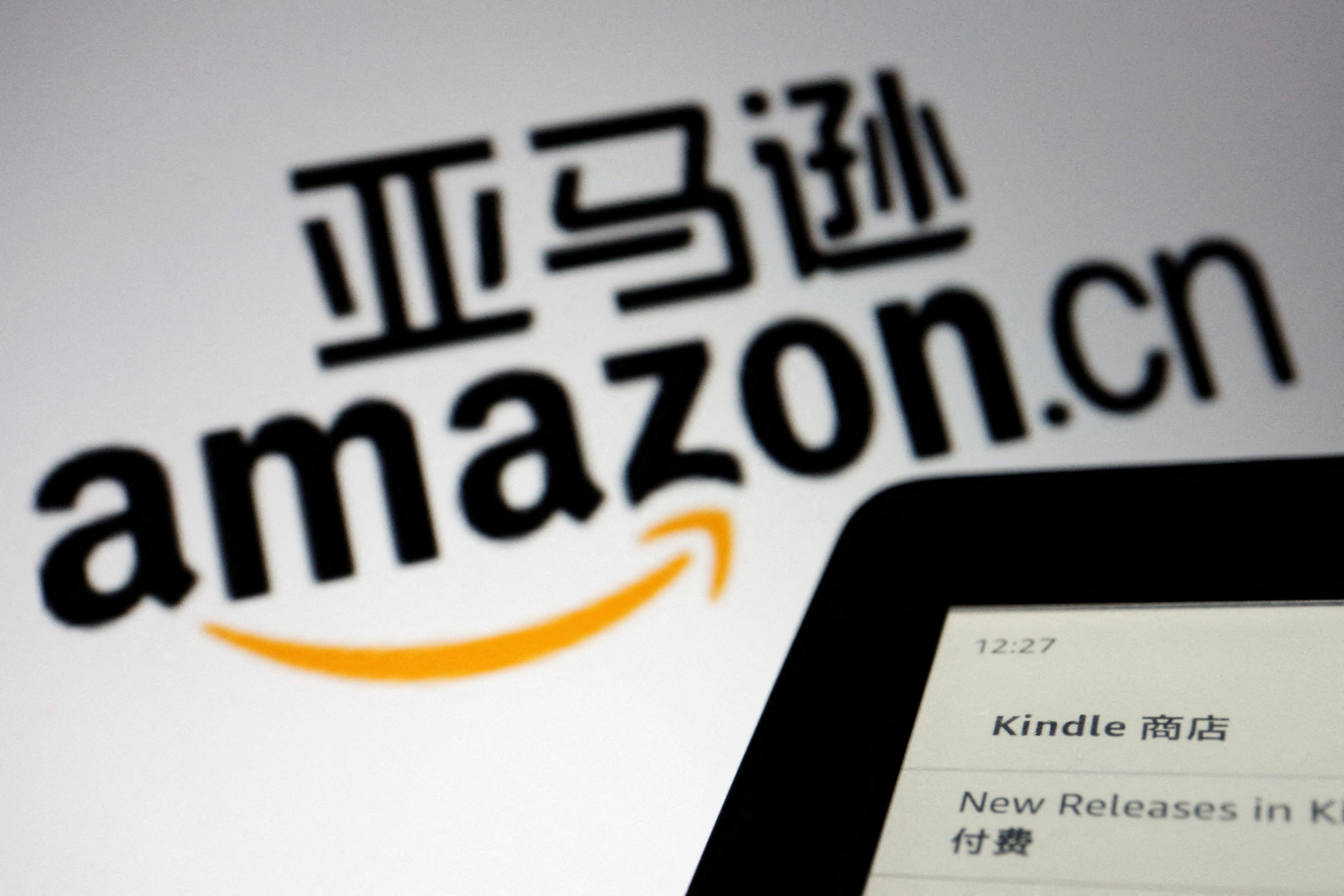 The sign of e-commerce website Amazon China is seen next to a Kindle e-reader displayed in this illustration