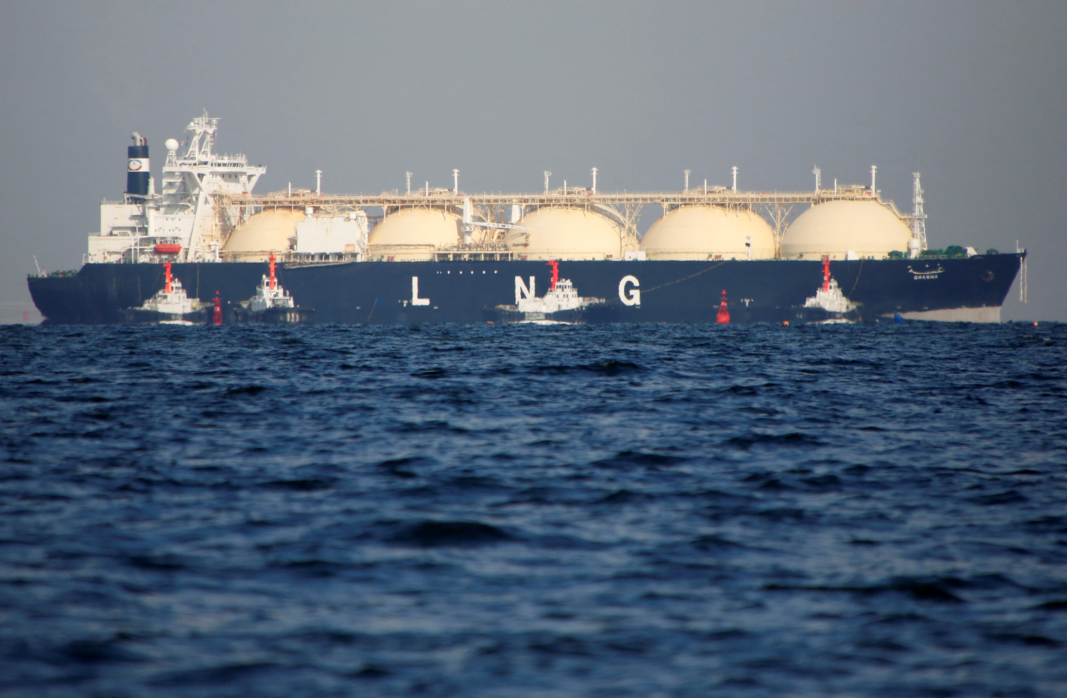 A LNG tanker is tugged towards a thermal power station in Futtsu