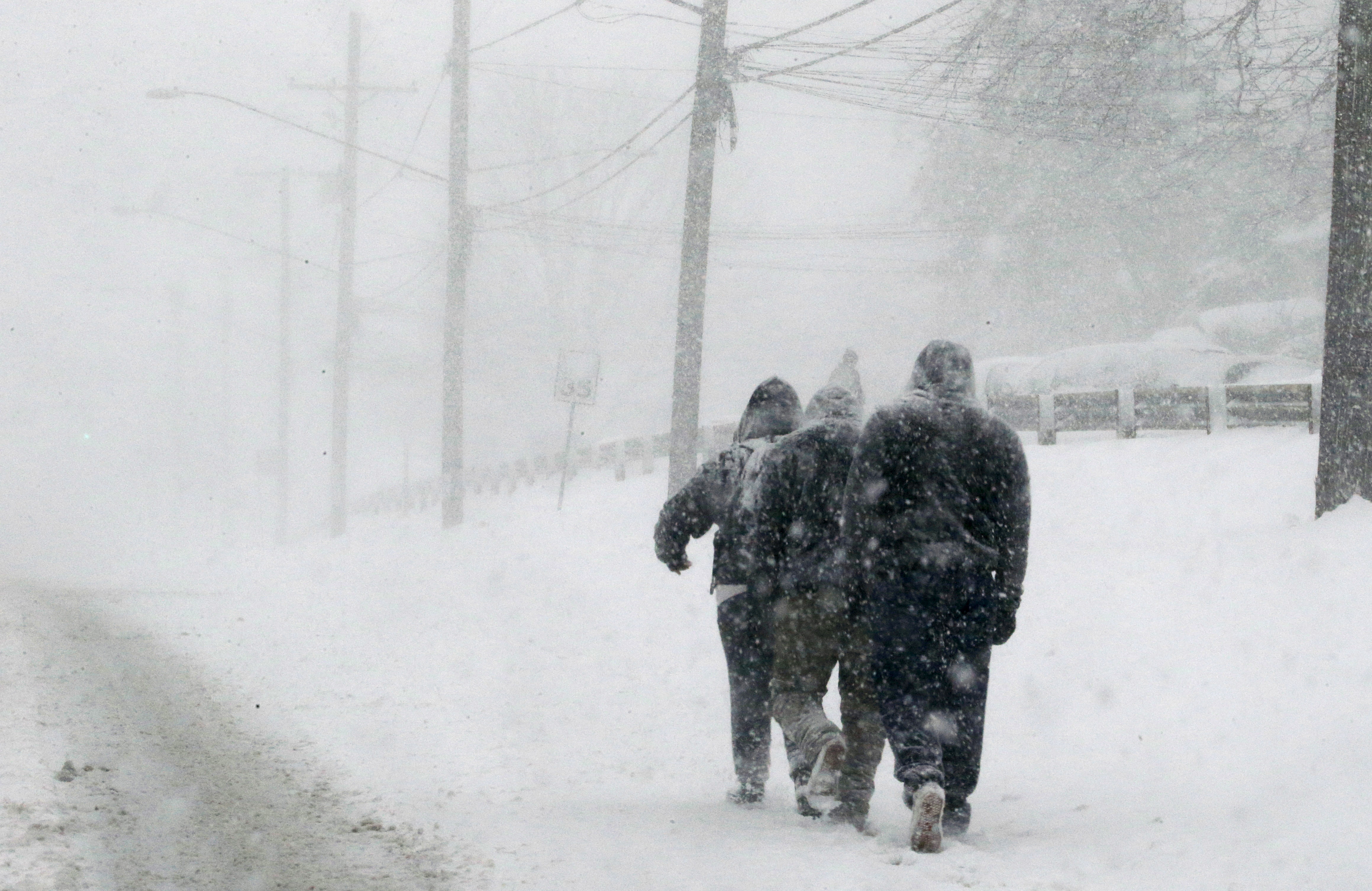 Pedestrians walk through a winter snow storm on New Hampshire Avenue in the Washington suburb of Silver Spring, Maryland