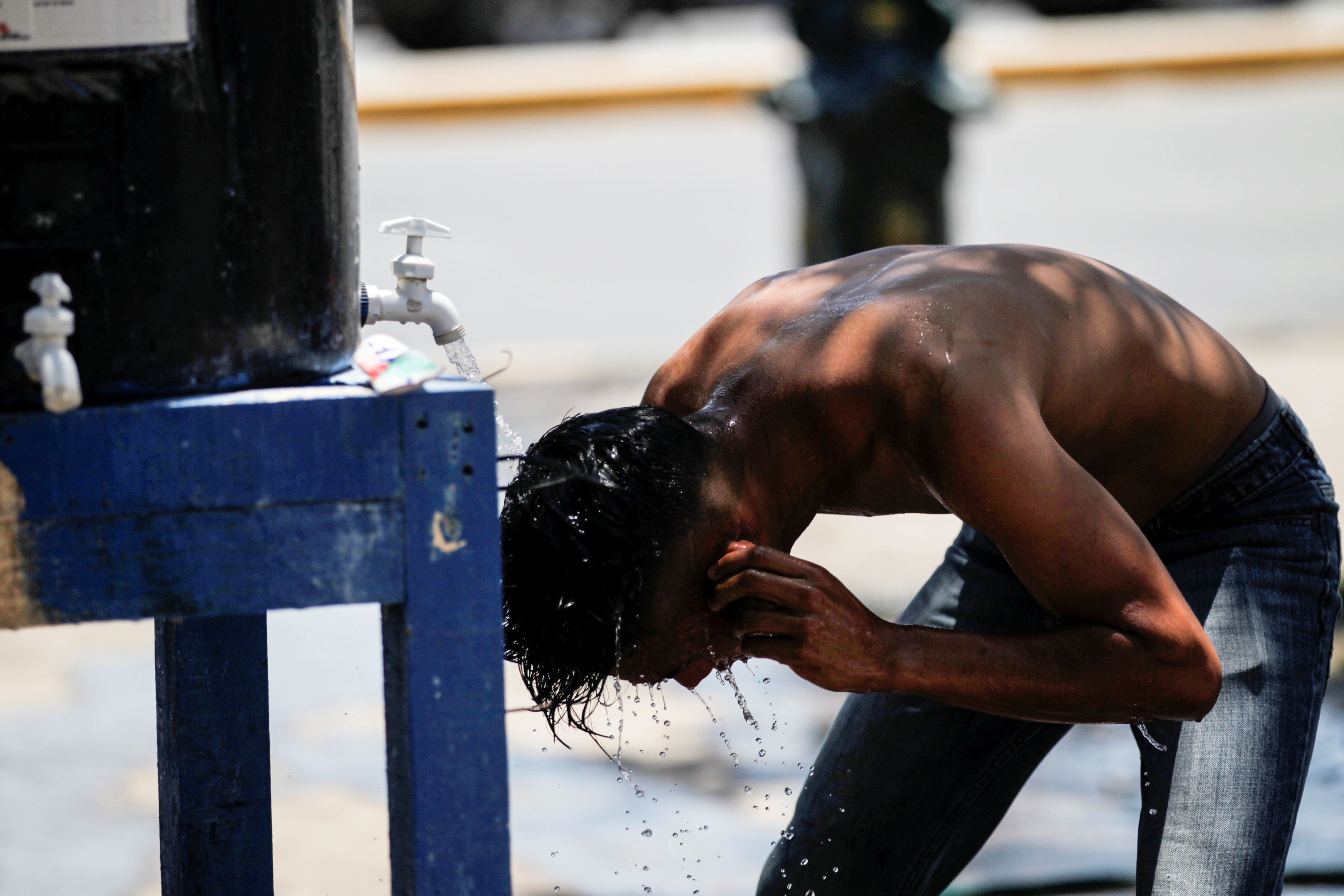 An asylum-seeking migrant youth, who was apprehended with their parents and returned to Mexico under Title 42 after crossing the border from Mexico into the U.S., bathes in a public square where hundreds of migrants live in tents, in Reynosa