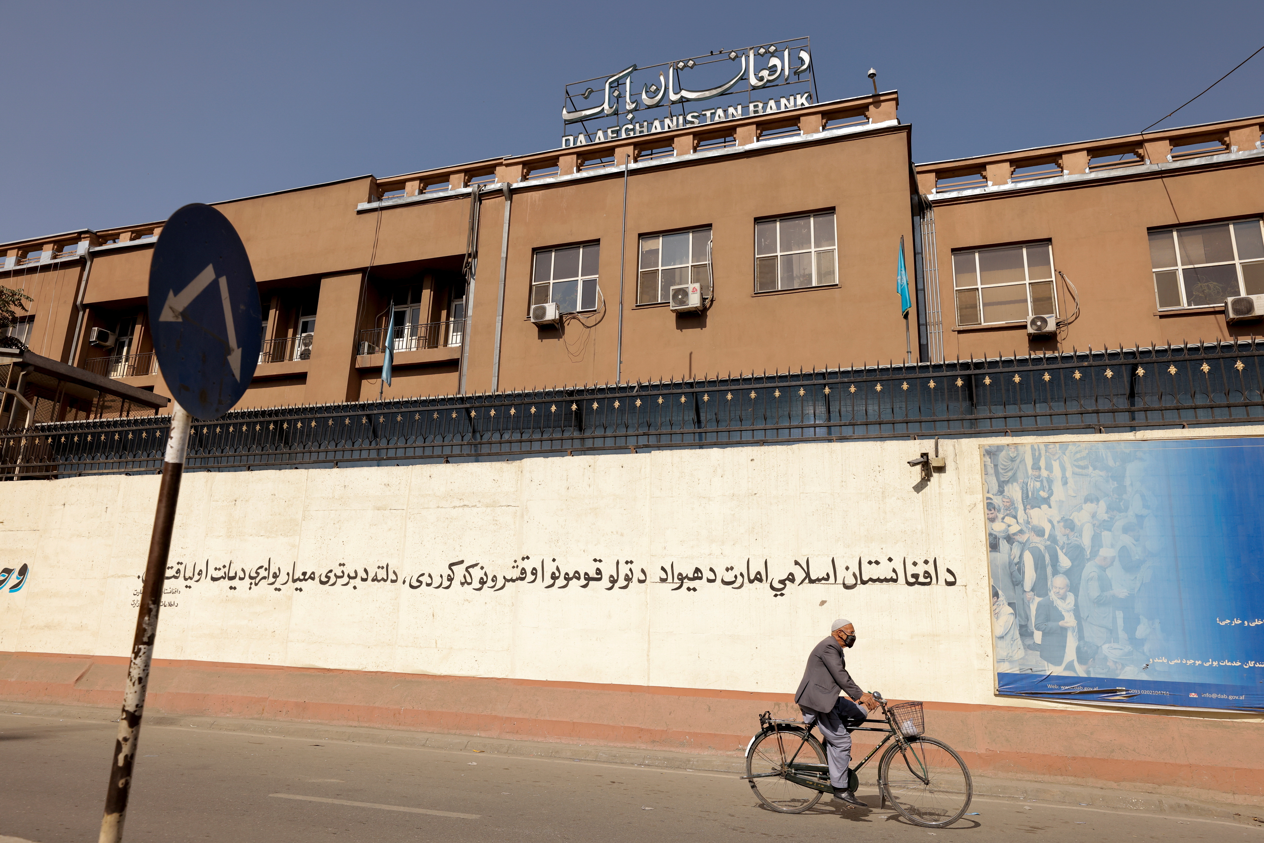 A man rides a bike in front of the Bank of Afghanistan in Kabul