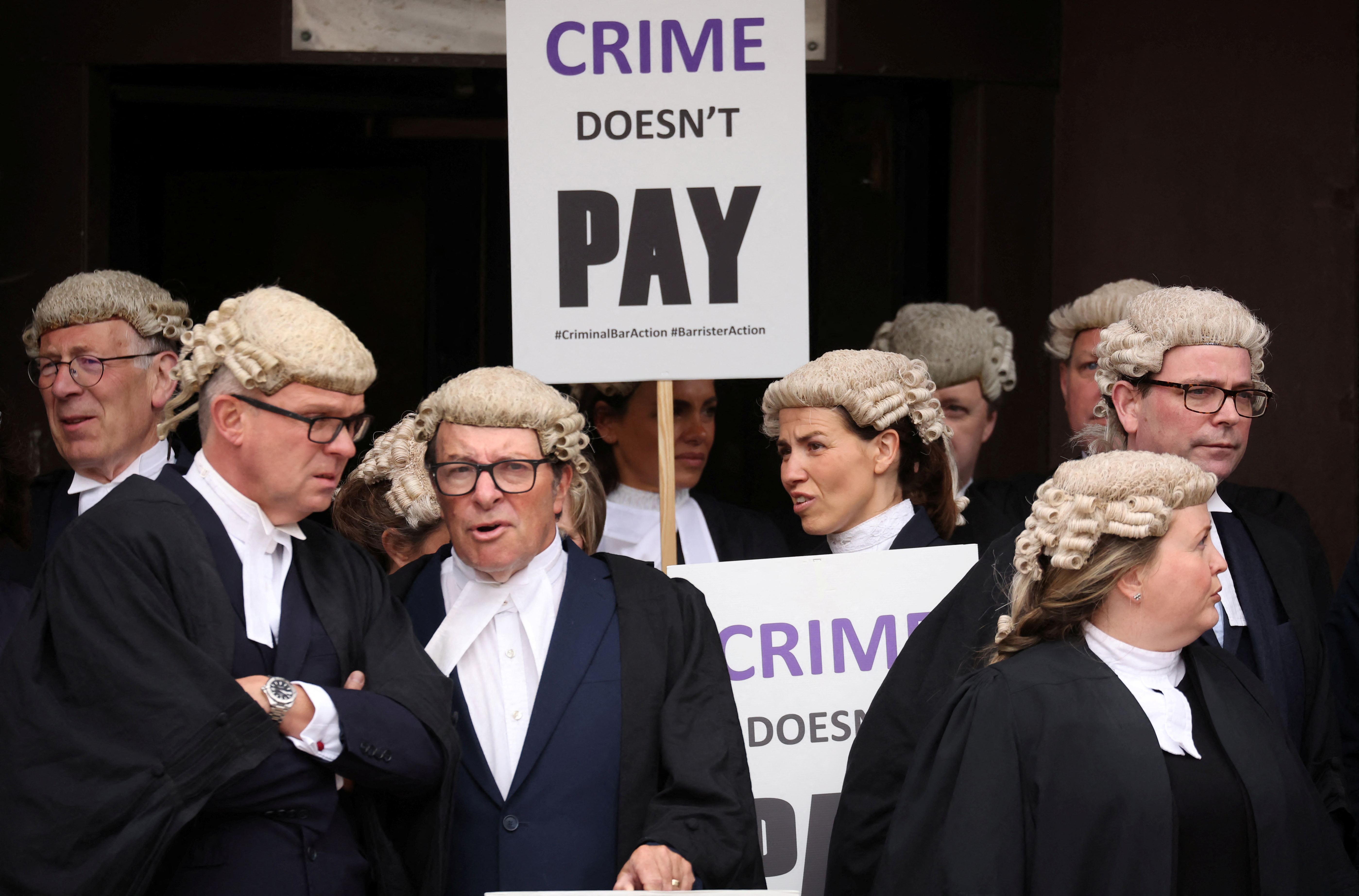 Barristers stand together during a strike by criminal barristers outside Liverpool Crown Court in Liverpool, Britain