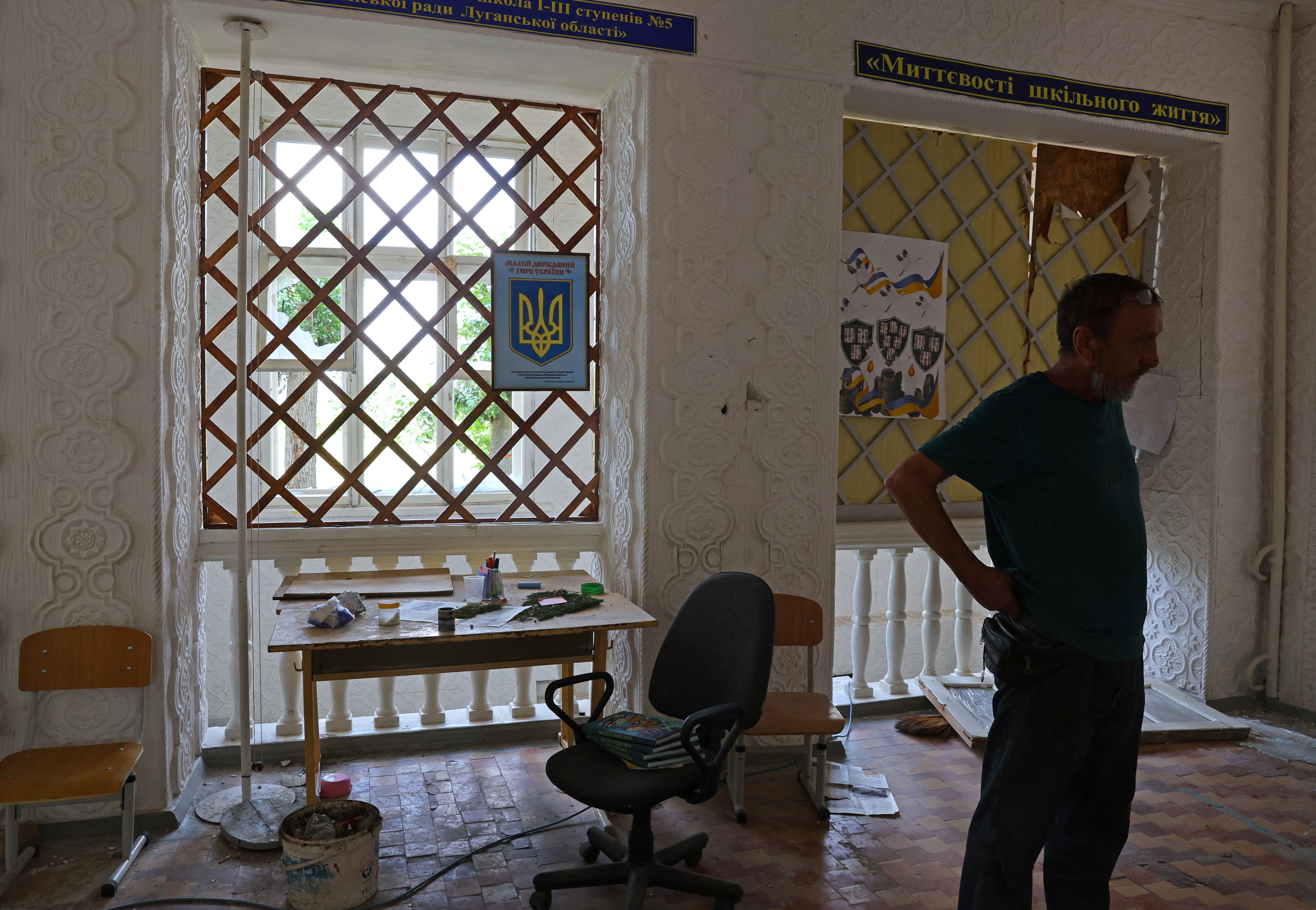 Local resident Andrey Butenko stands inside the damaged school building where he lives in the basement in Lysychansk