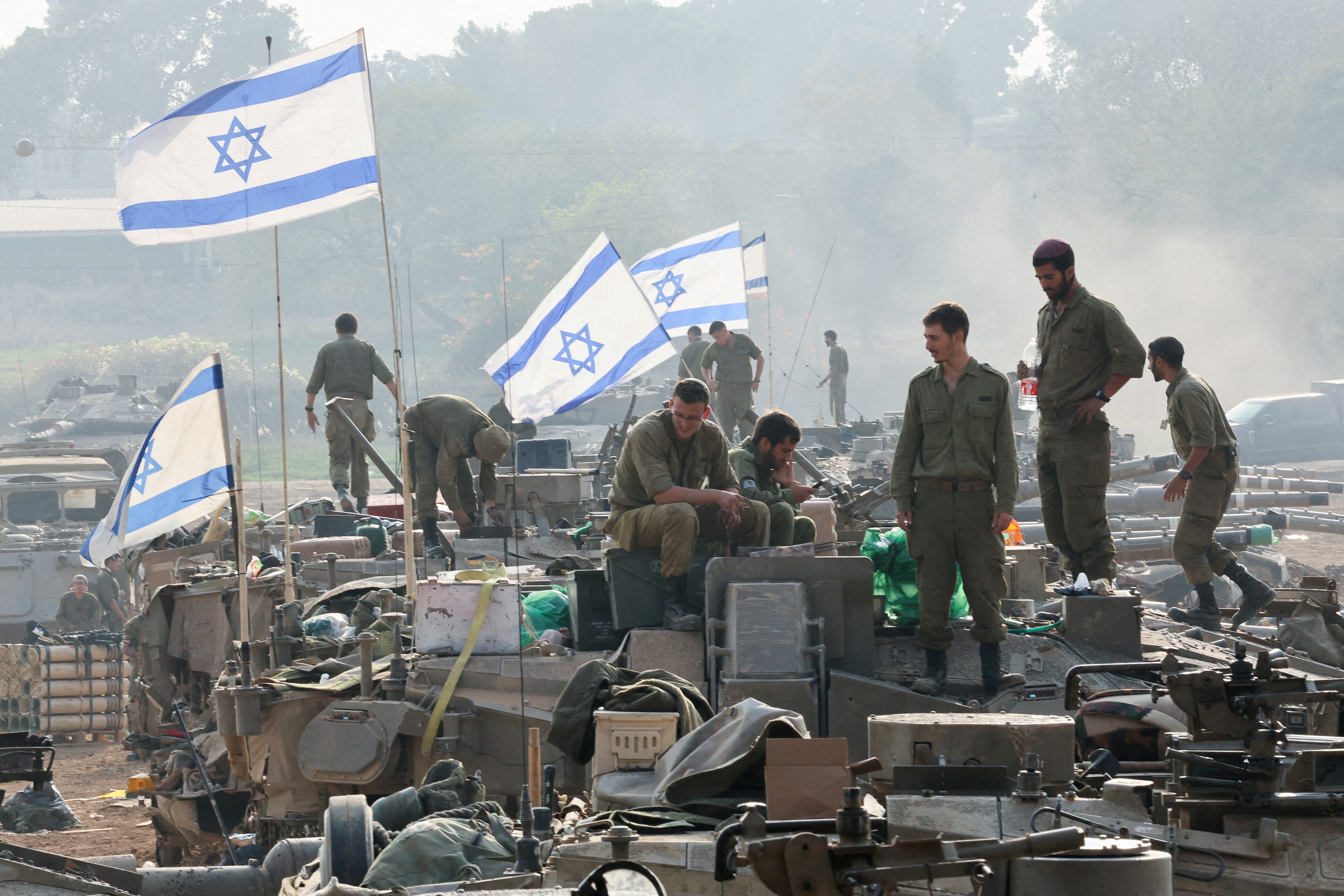 Israeli soldiers stand on tanks, near the Israel-Gaza border