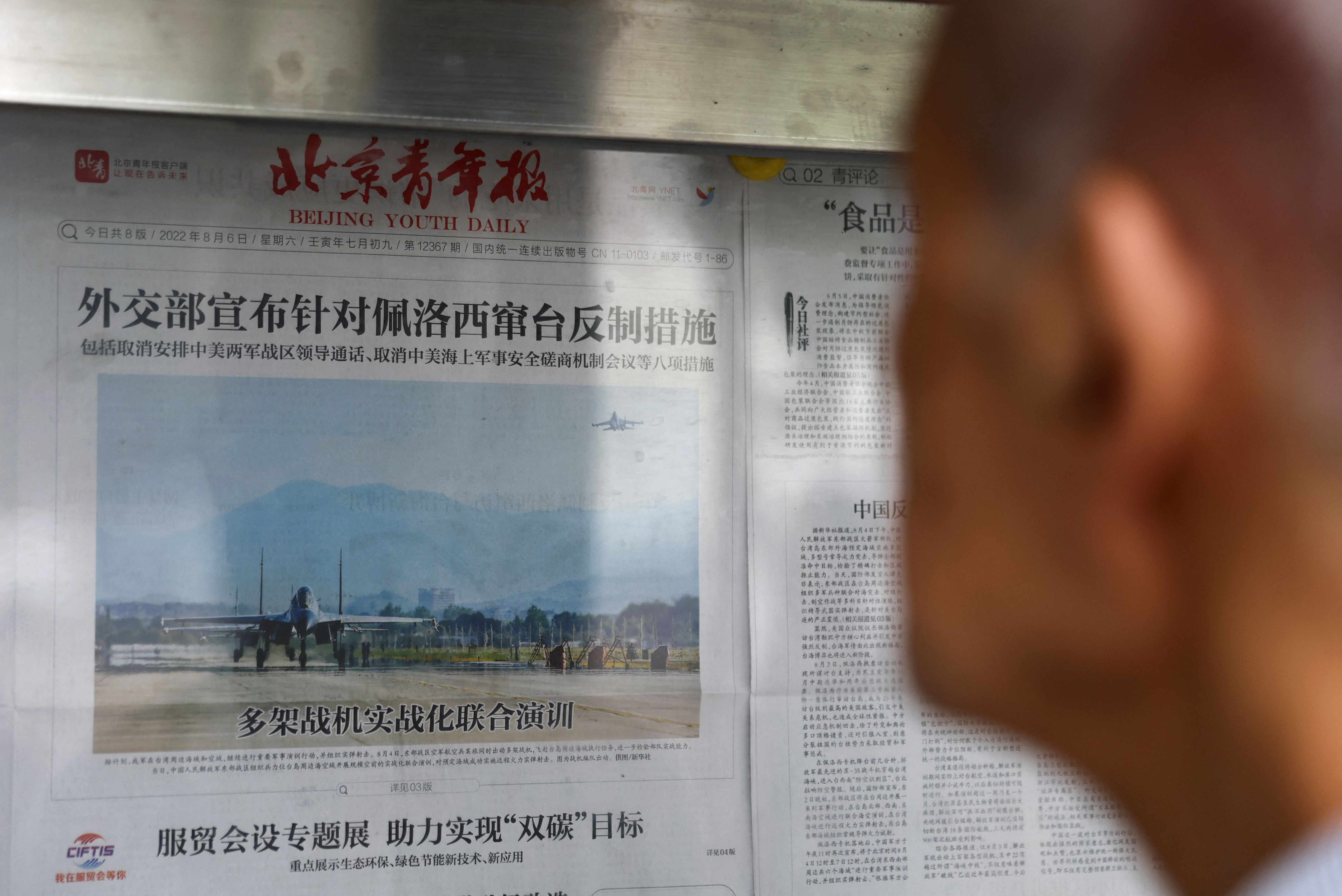 مردی گزارش روزنامه ای را با تصویری از تمرینات نظامی در نزدیکی تایوان توسط فرماندهی تئاتر شرق ارتش آزادیبخش خلق چین (PLA) در صفحه اول، در غرفه روزنامه در پکن می خواند.