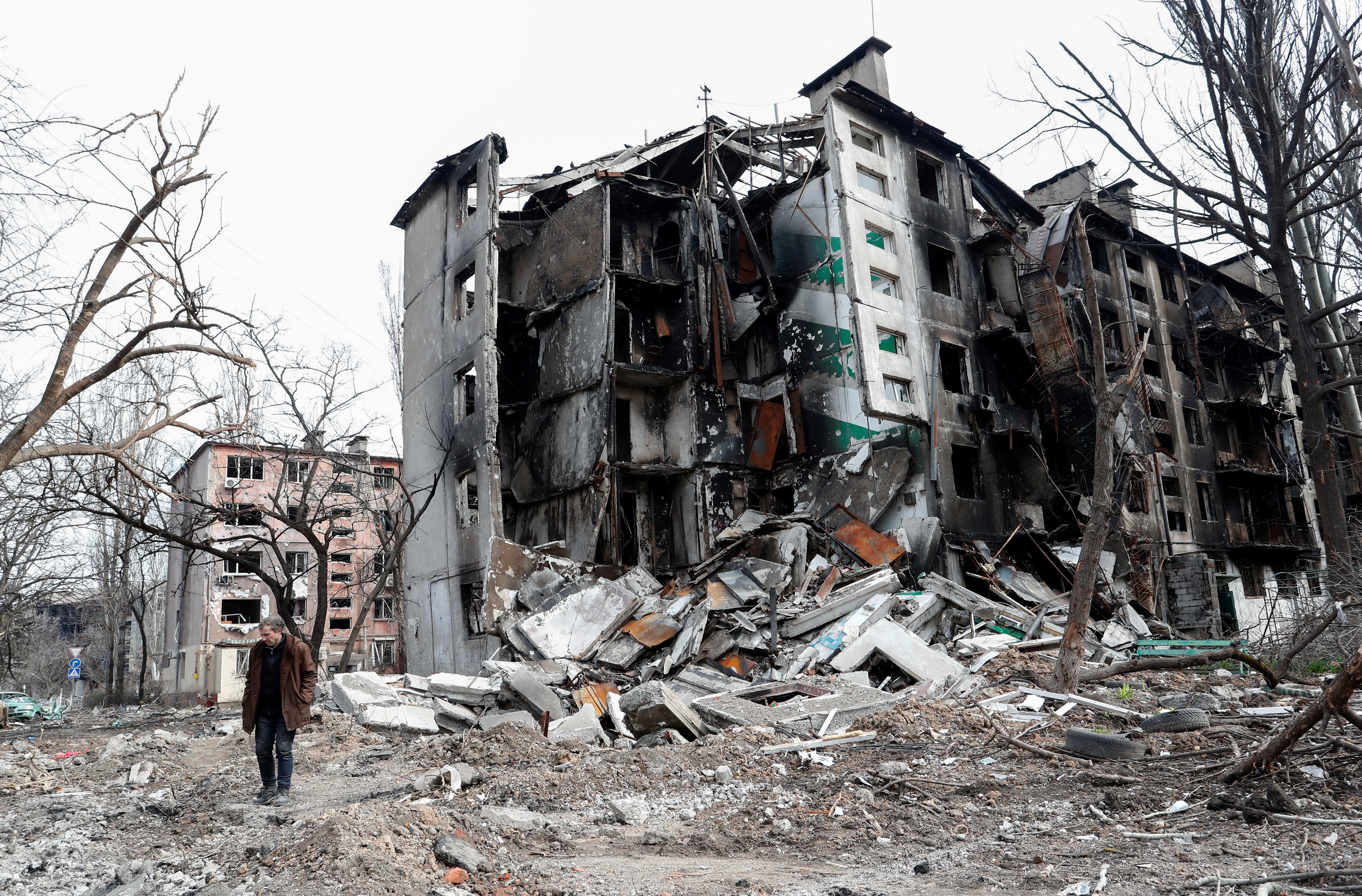 A man walks near a destroyed residential building in Mariupol