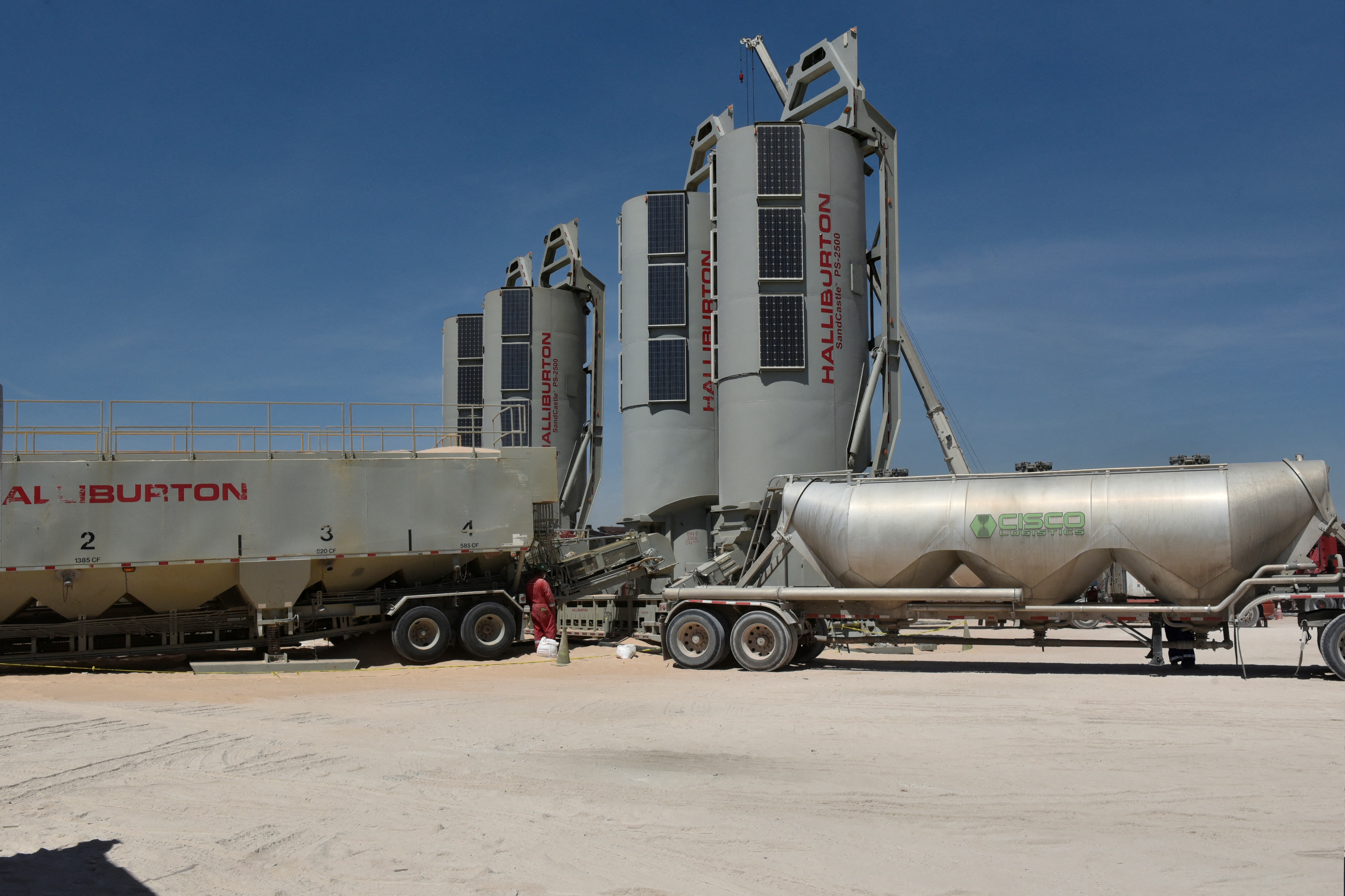 Trucks filled with sand used in the fracking process are seen on a well site leased by Oasis Petroleum in the Permian Basin oil production area near Wink
