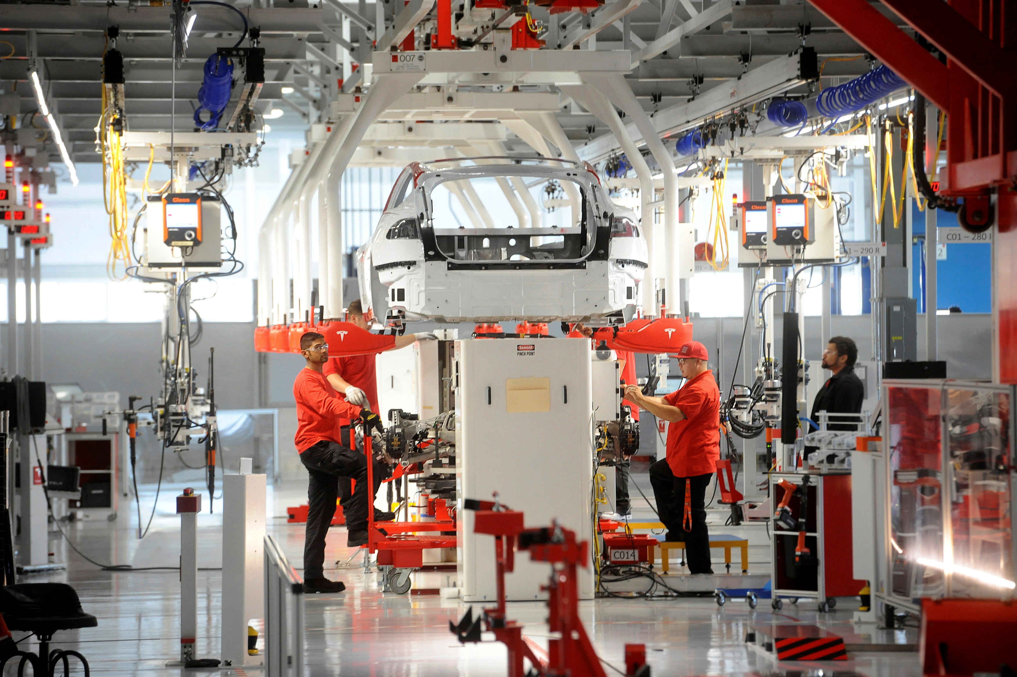 Tesla workers examine a Model S used for training and tool calibration at the company's factory in Fremont
