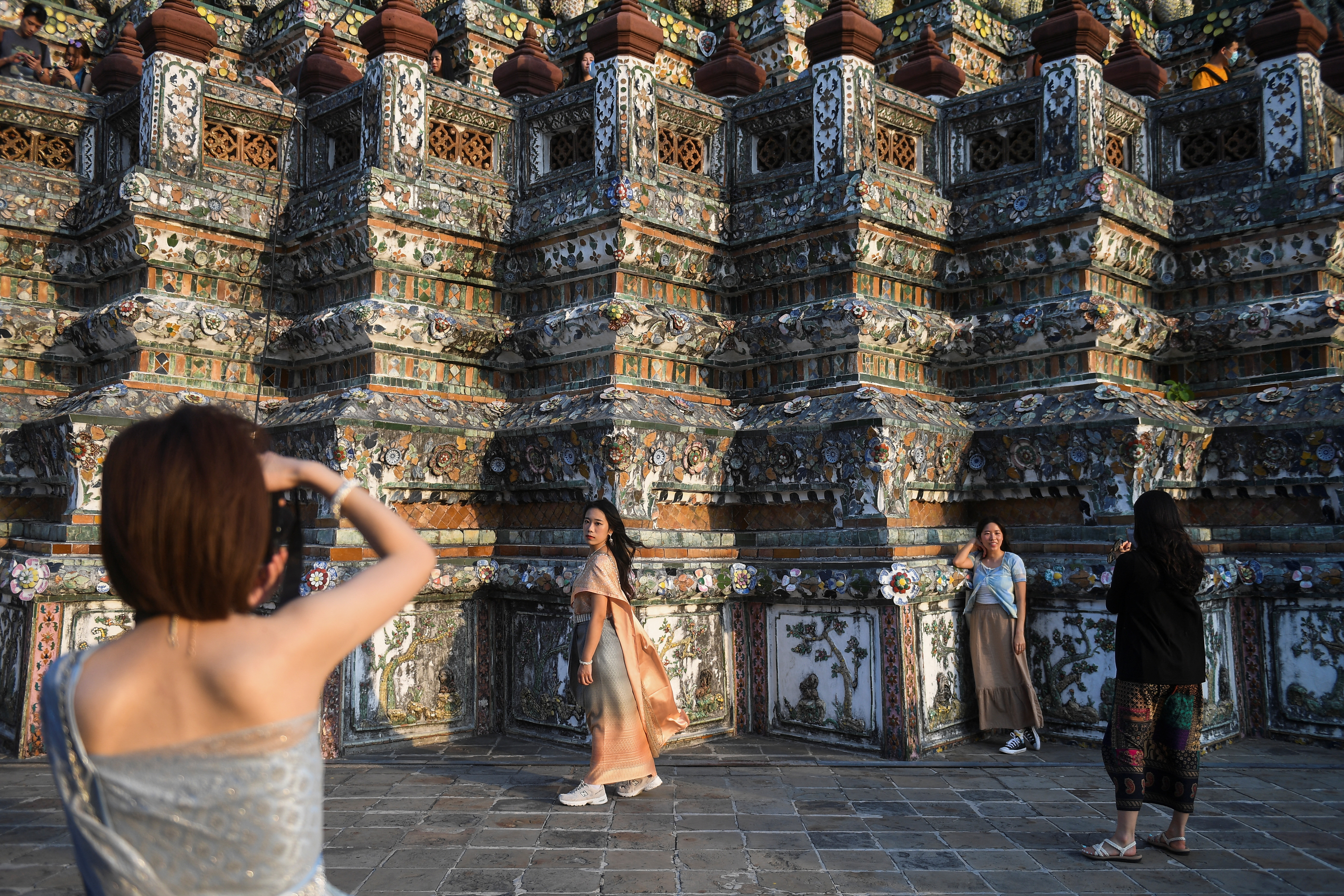 Tourists dressed in traditional Thai costumes visit Wat Arun temple in Bangkok