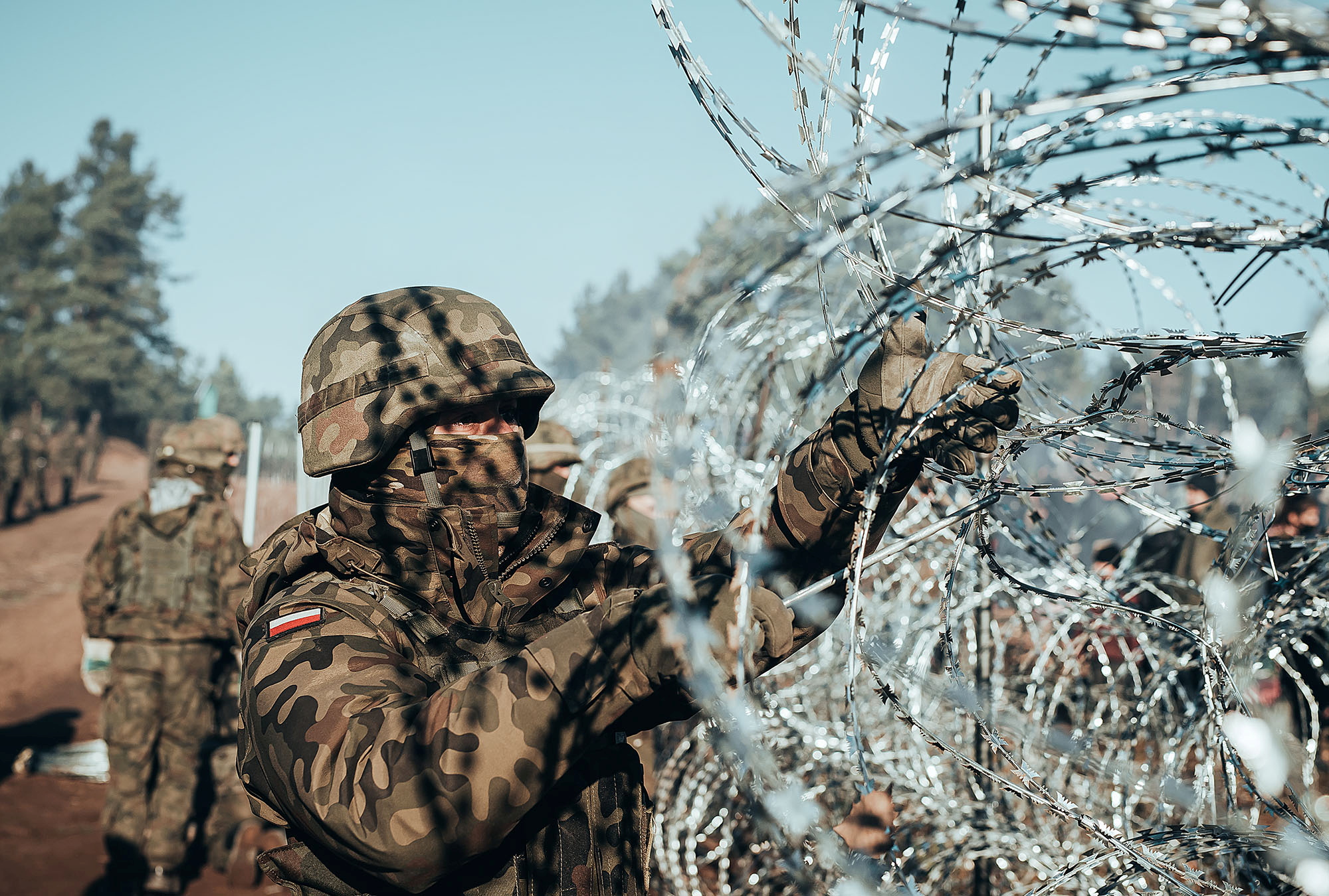 A Polish soldier instals barbed wire on the Poland/Belarus border near Kuznica