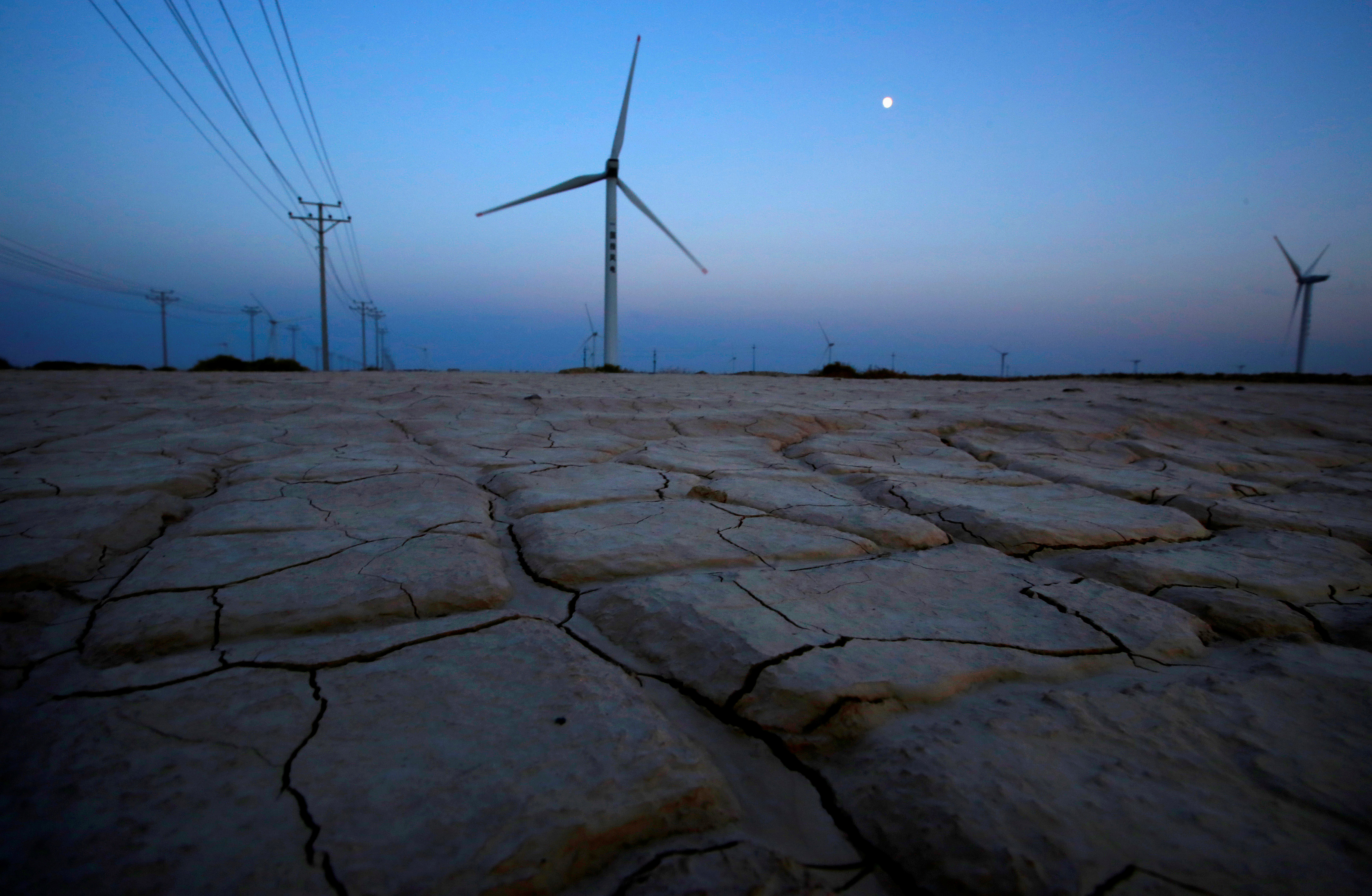 Cracked earth marks a dried-up area near a wind turbine used to generate electricity at a wind farm in Guazhou, 950km (590 miles) northwest of Lanzhou, Gansu Province