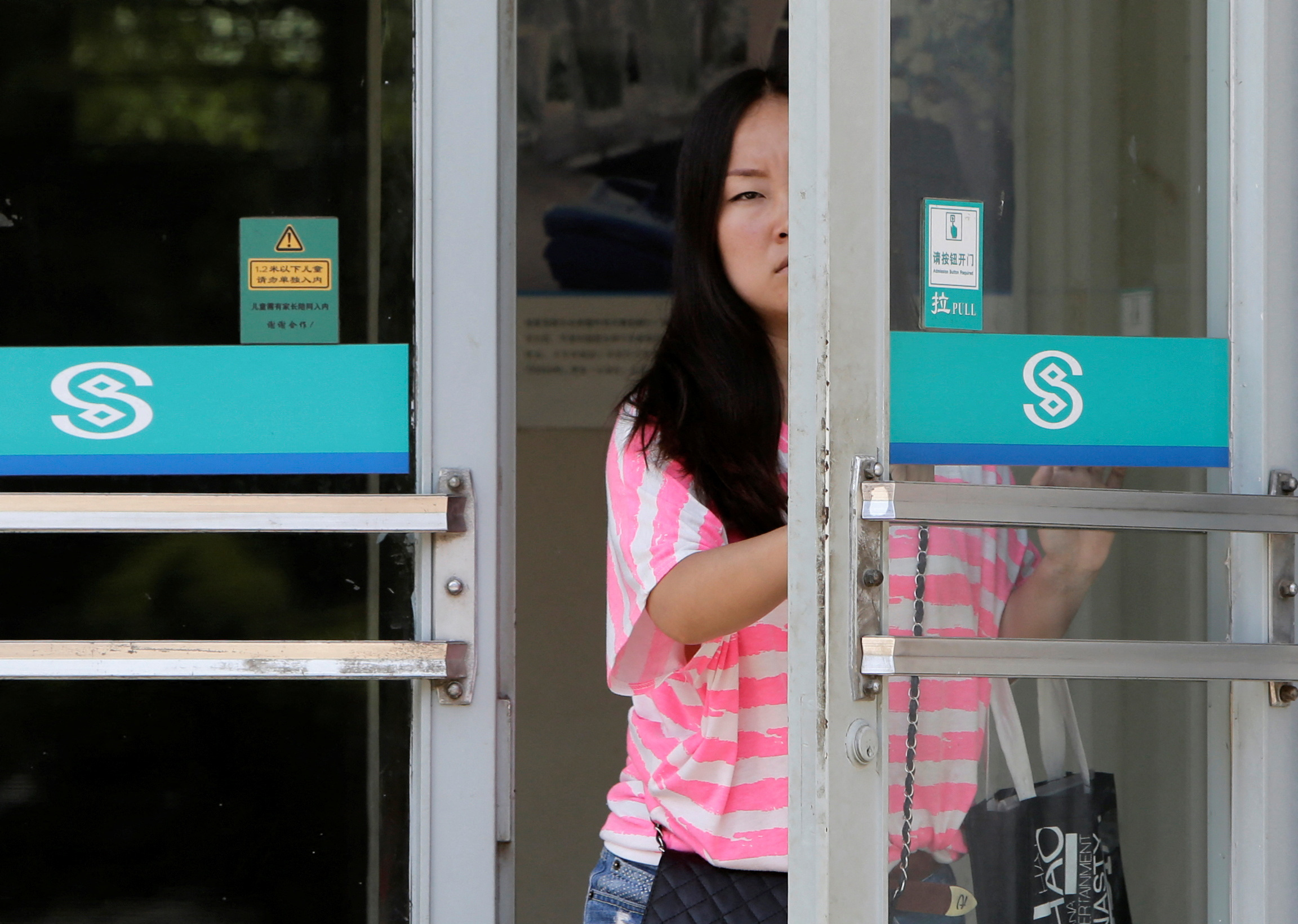 A customer opens the door to a branch of China Minsheng Bank in Beijing