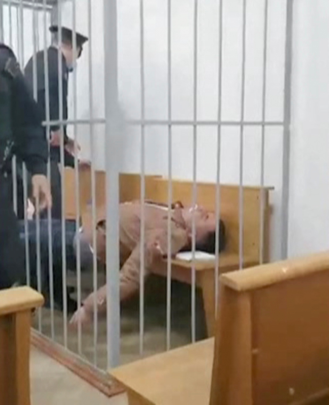 Belarusian prisoner Stepan Latypov lies on a bench after an attempt to cut his throat inside a defendant's cage in a courtroom in Minsk