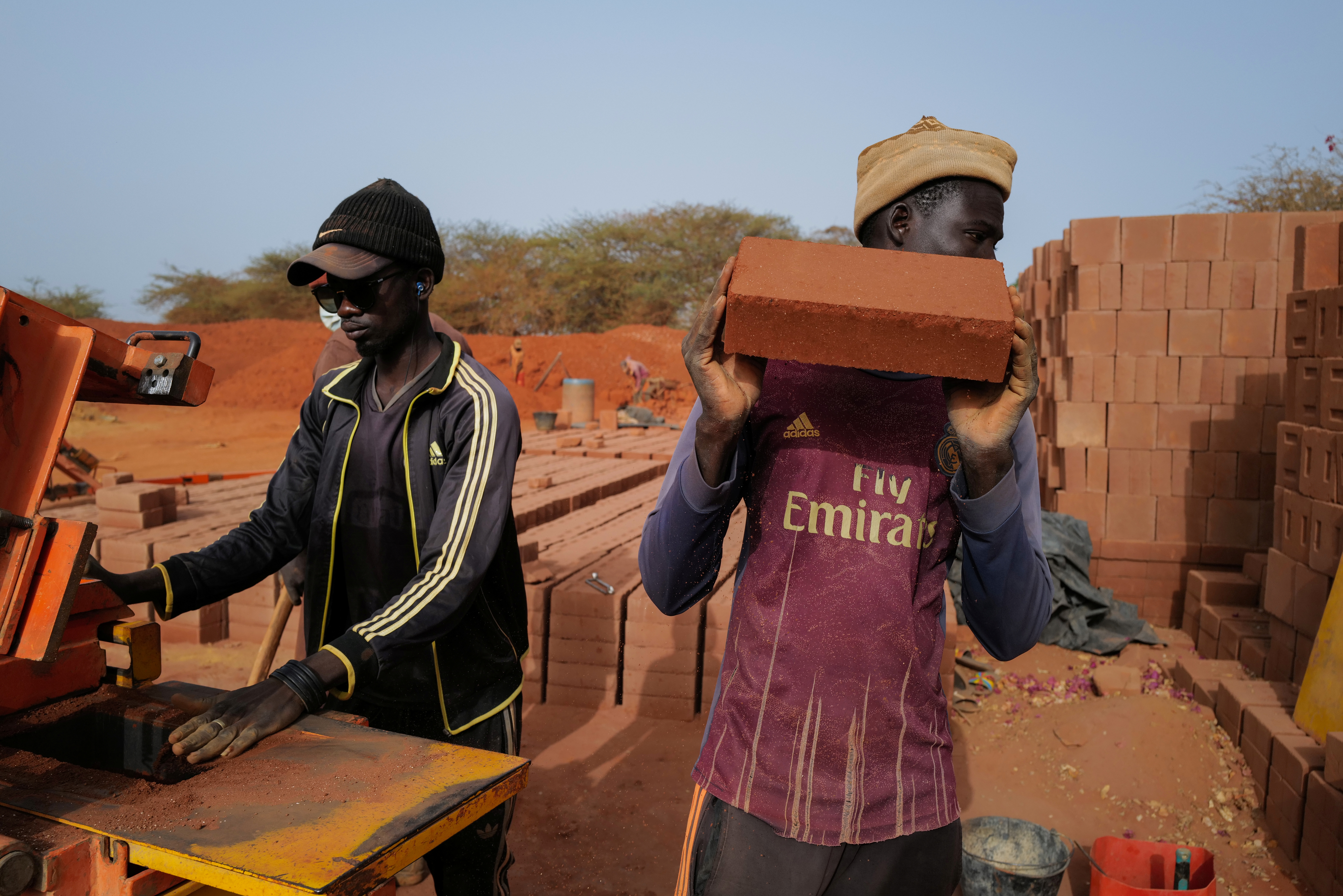 A worker carries a newly made brick at the Elementerre factory in Mbour