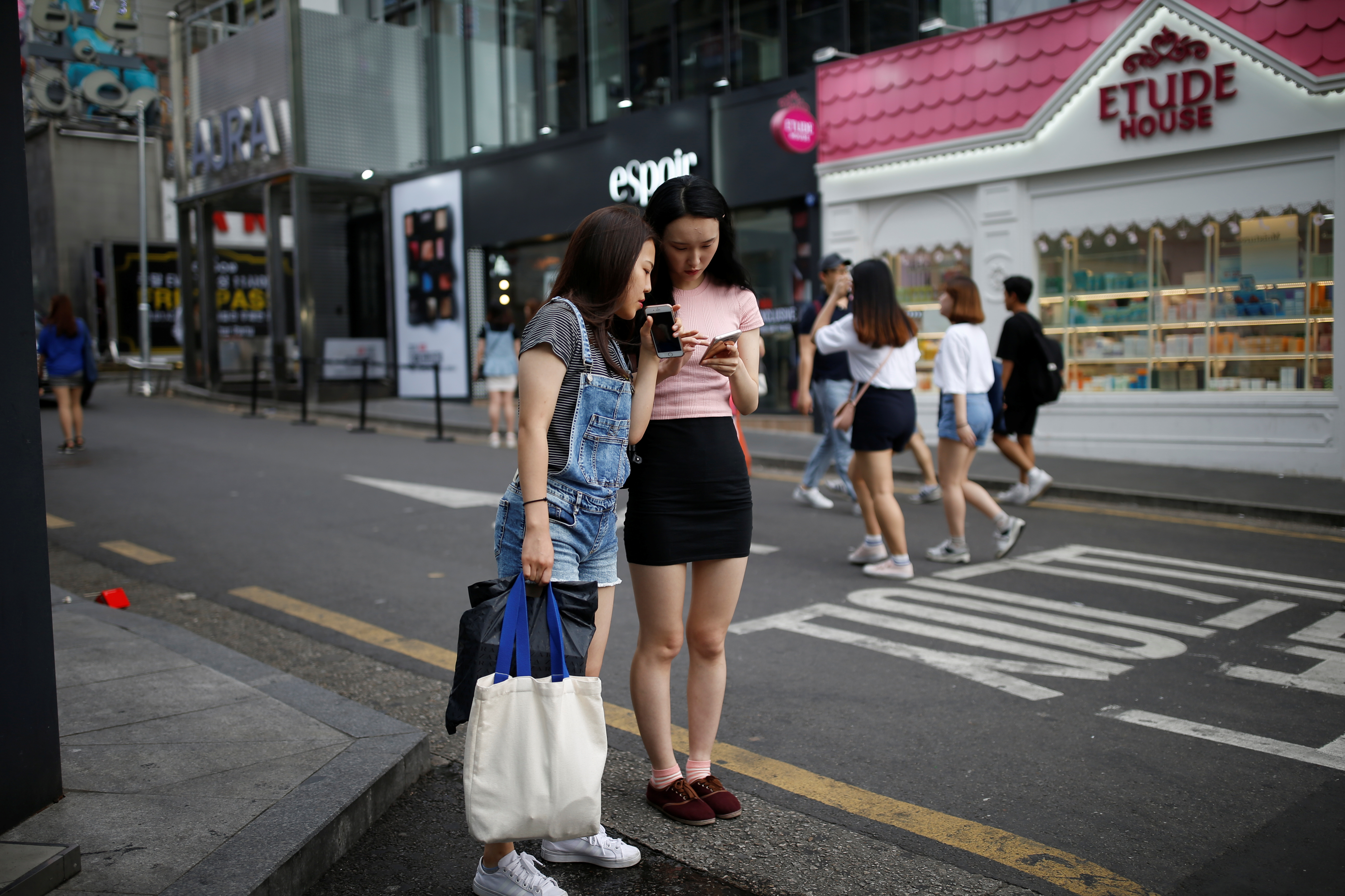Women look at their moblie phones in the Hongdae area of Seoul