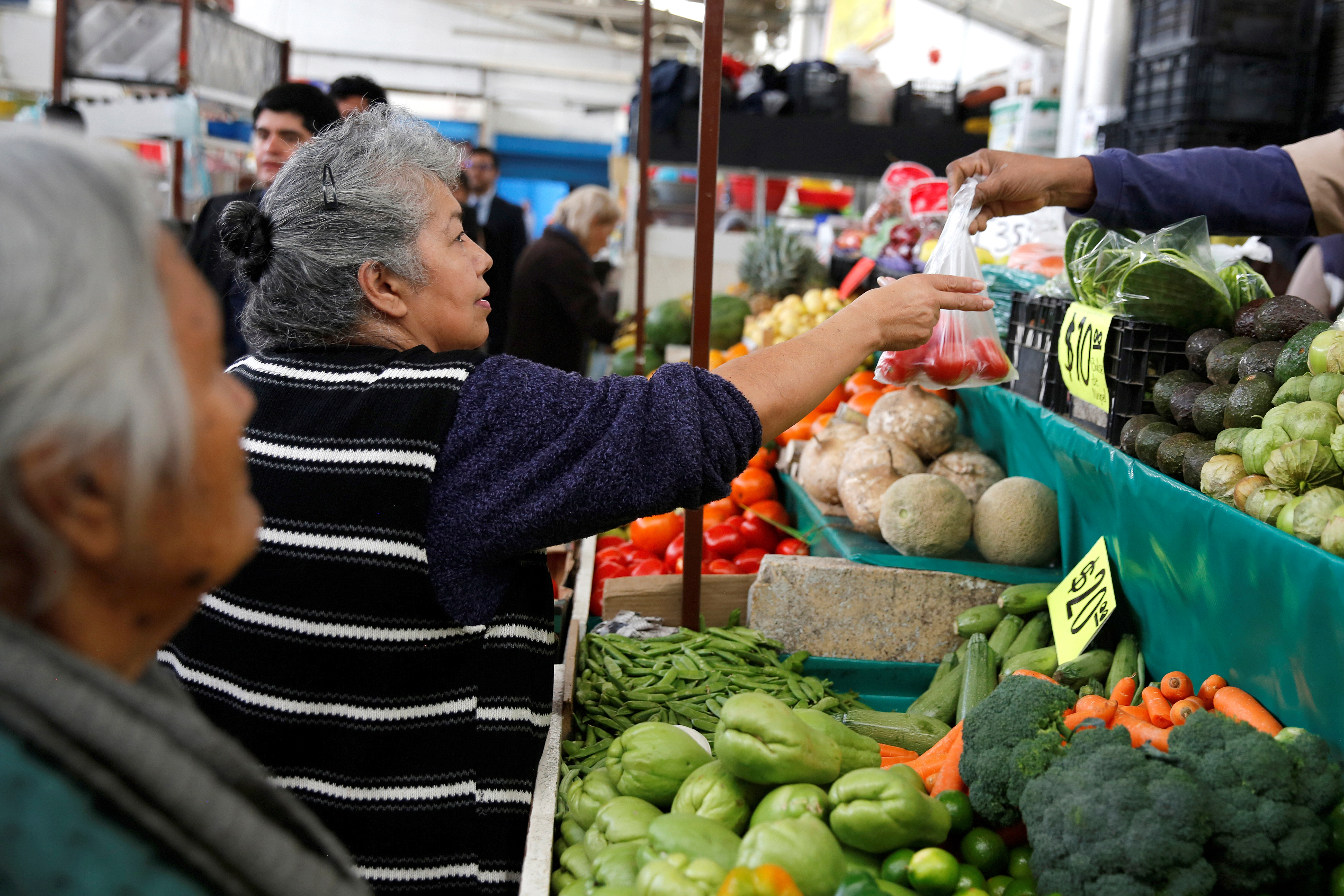 Woman buys tomatoes in a groceries stall at Granada market in Mexico City