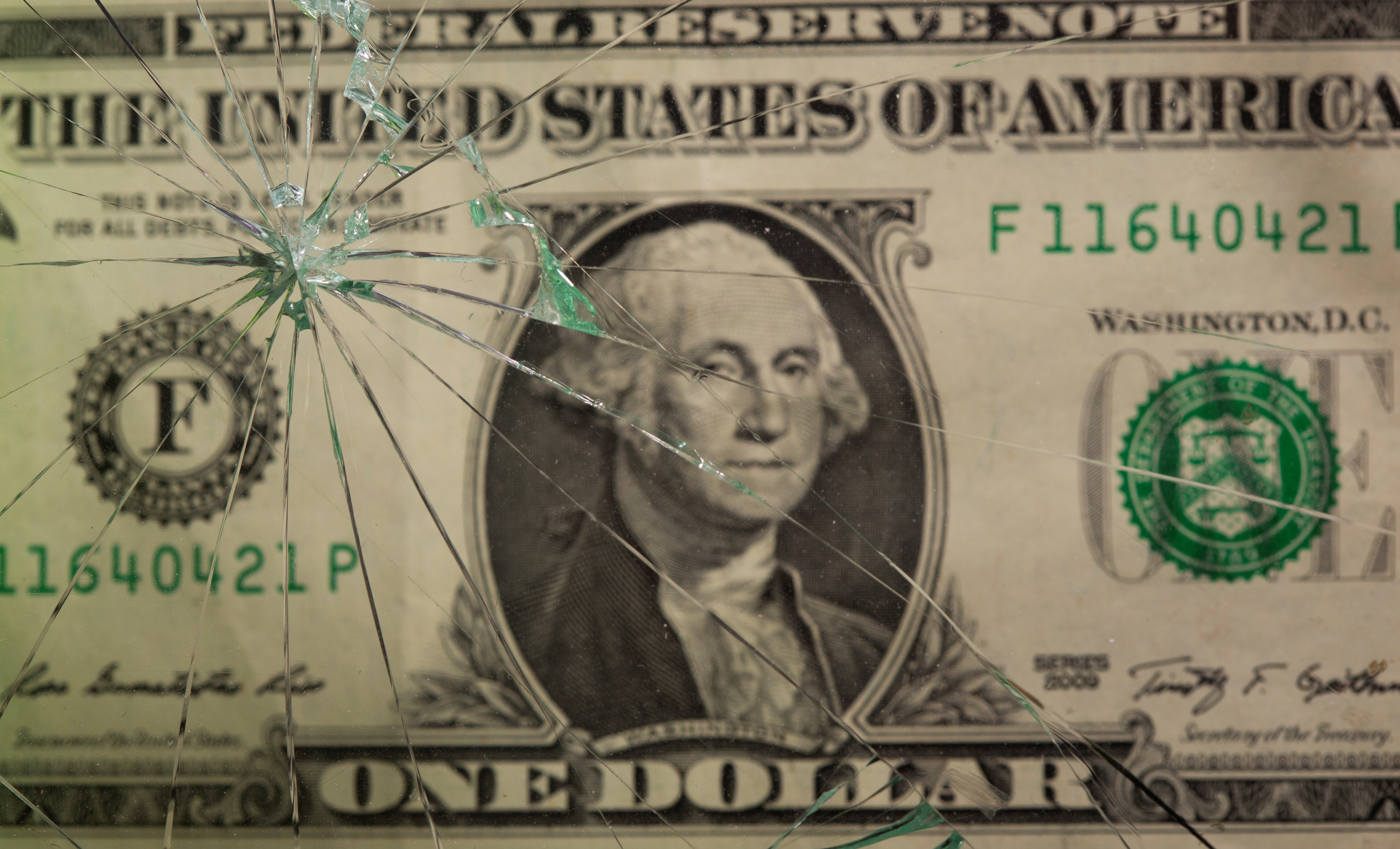 Dollar banknote seen through broken glass in this illustration