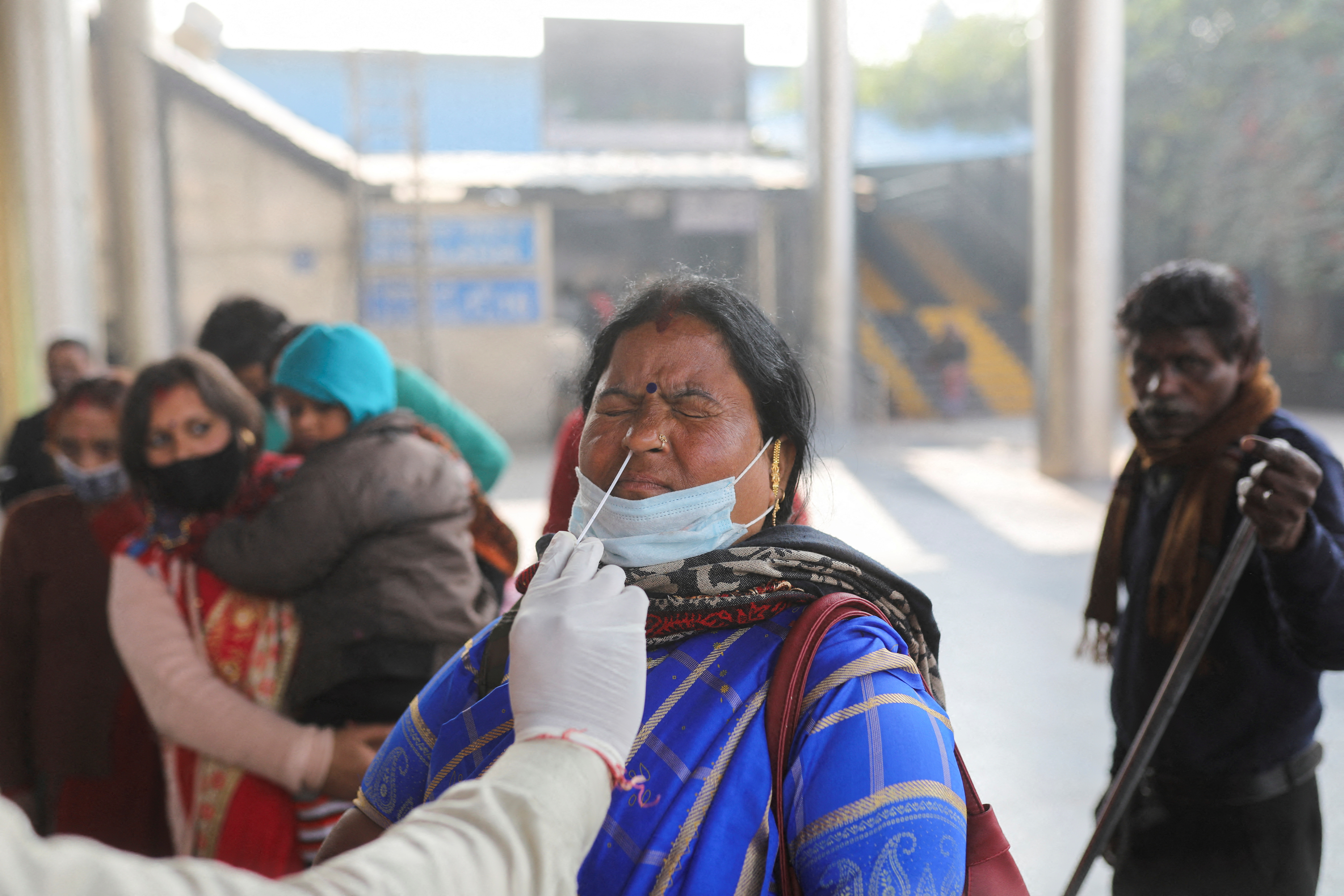 A healthcare worker collects a coronavirus disease (COVID-19) test swab sample from a woman amidst the spread of the disease, at a railway station in New Delhi