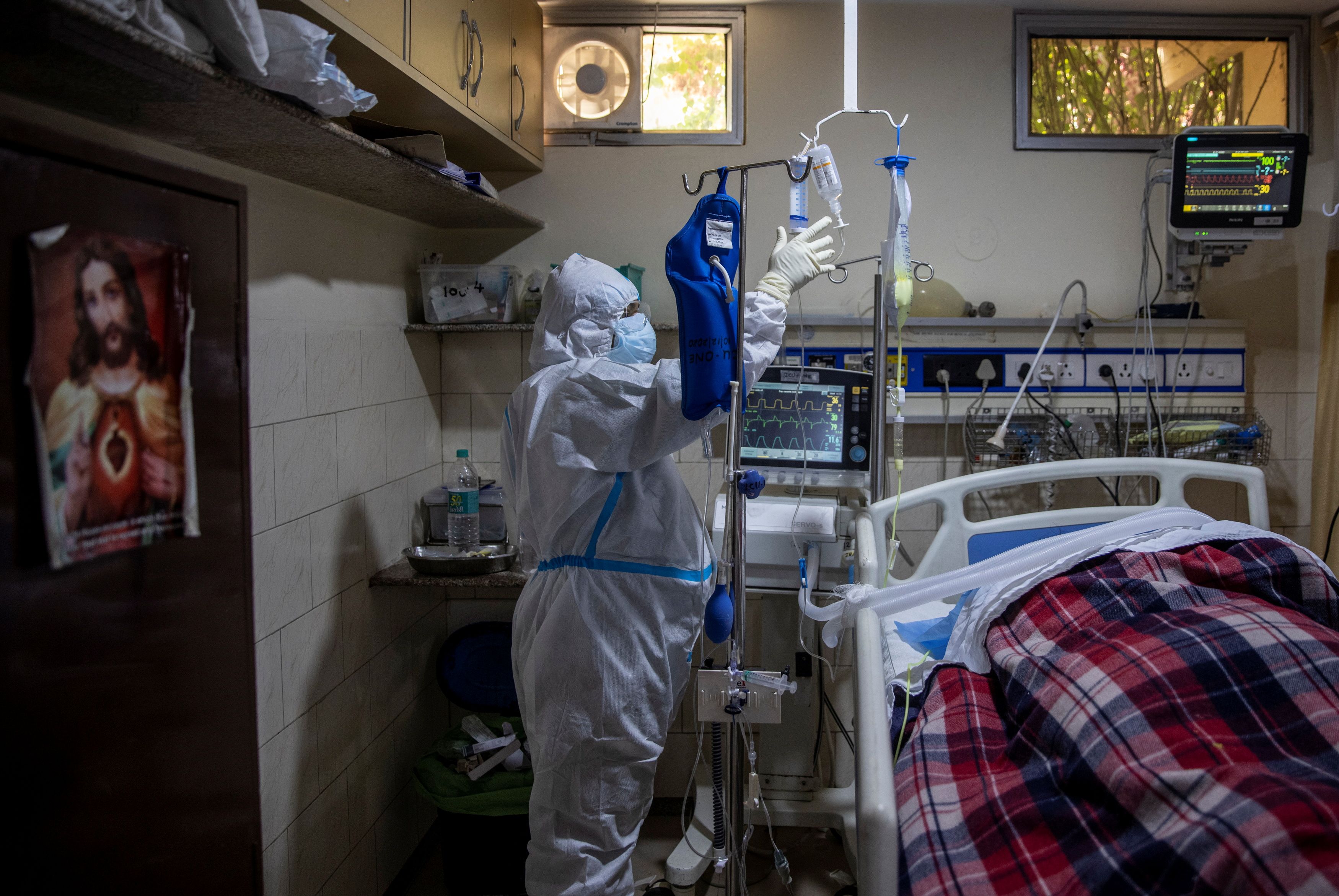A medical worker tends to a patient suffering from COVID-19, inside the ICU ward at Holy Family Hospital in New Delhi