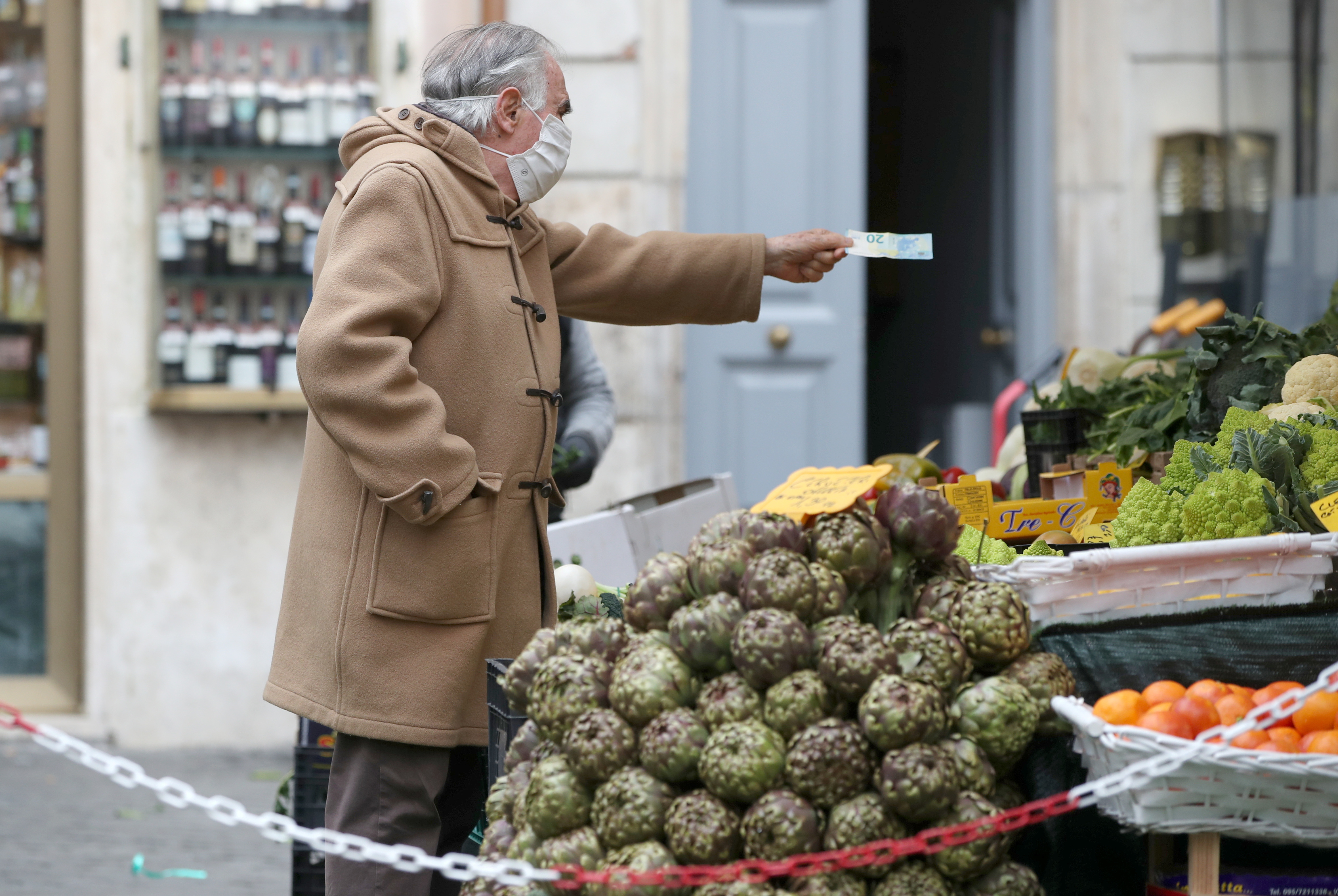 A man shops groceries at an open-air market as the government is due to announce stricter coronavirus disease (COVID-19) restrictions, in Rome, Italy, March 12, 2021. REUTERS/Yara Nardi