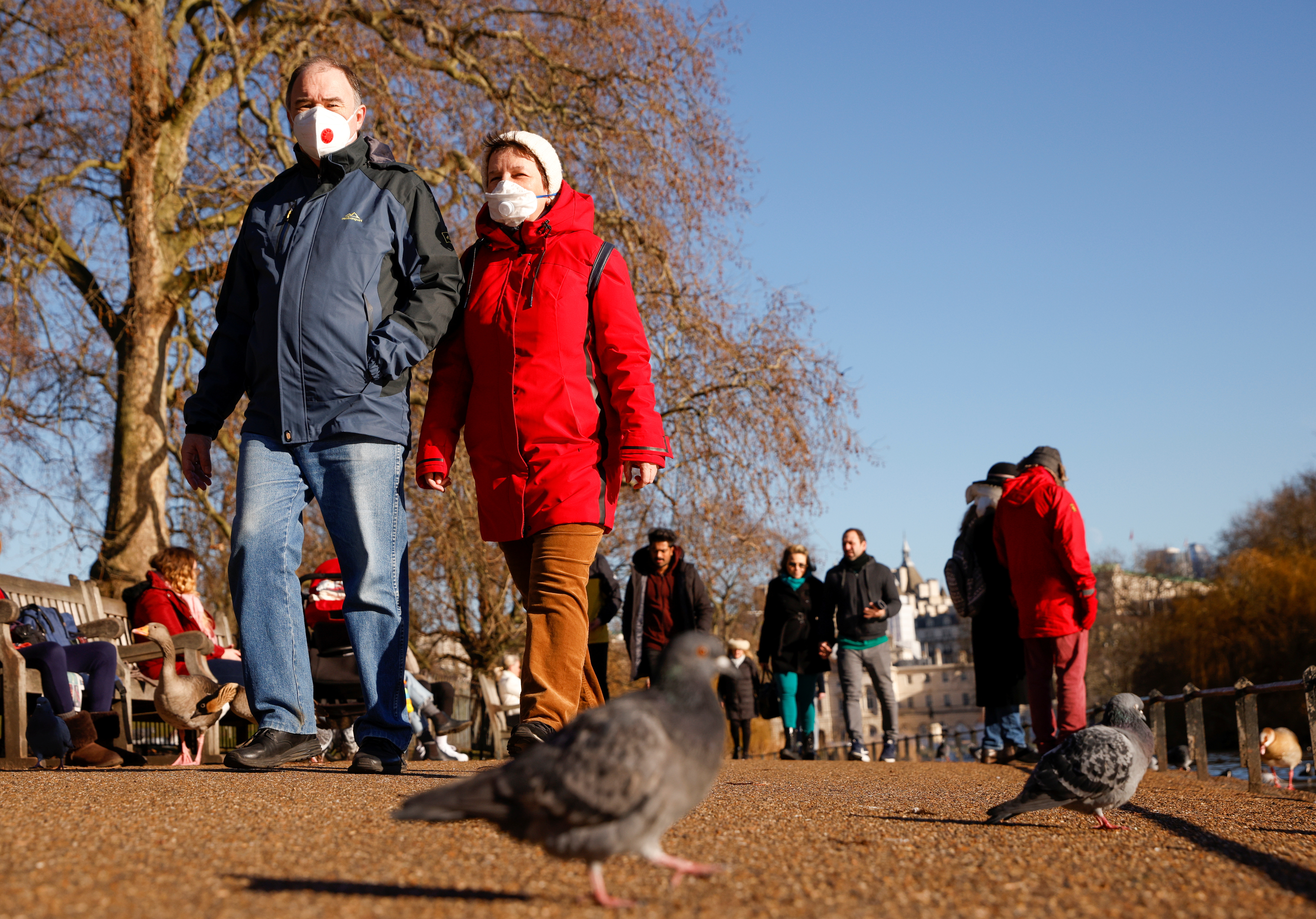 People wearing face masks walk in St James's Park in London