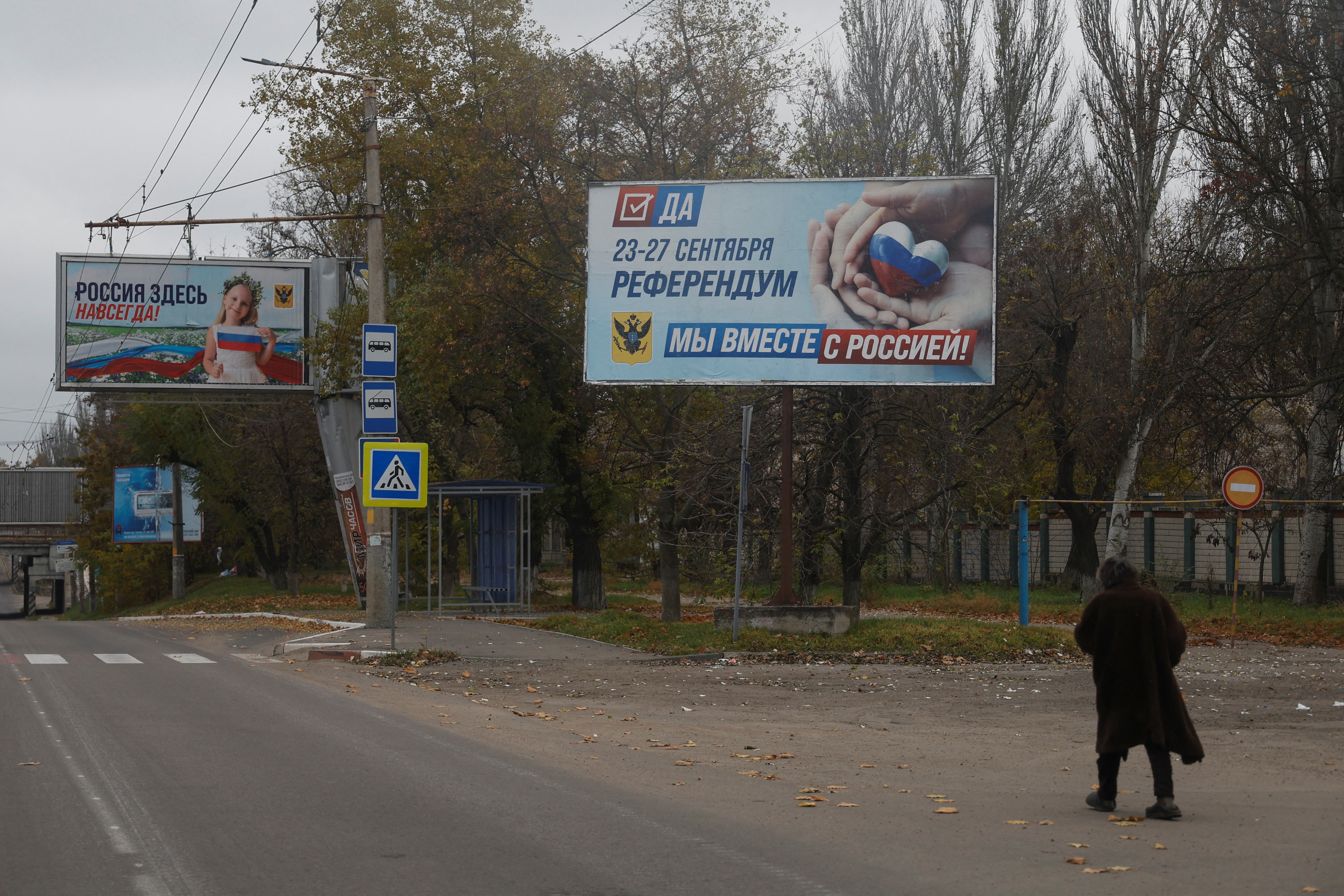 Local woman walks next to banners with Russian propaganda after Russia's retreat from Kherson, in Kherson