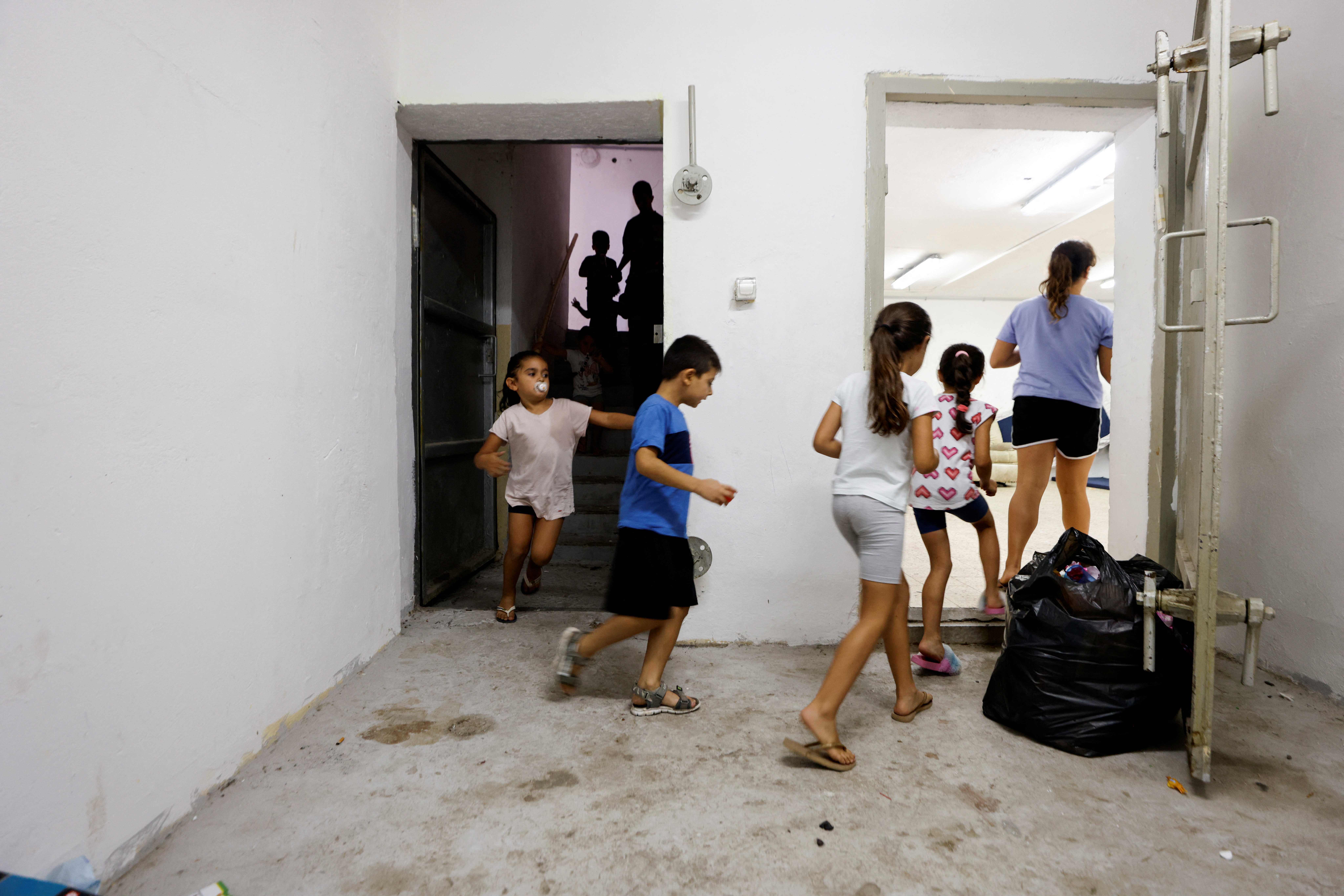 Israeli children run inside a bomb shelter as siren goes off indicating incoming rockets fired from Gaza towards Israel, in Ashkelon