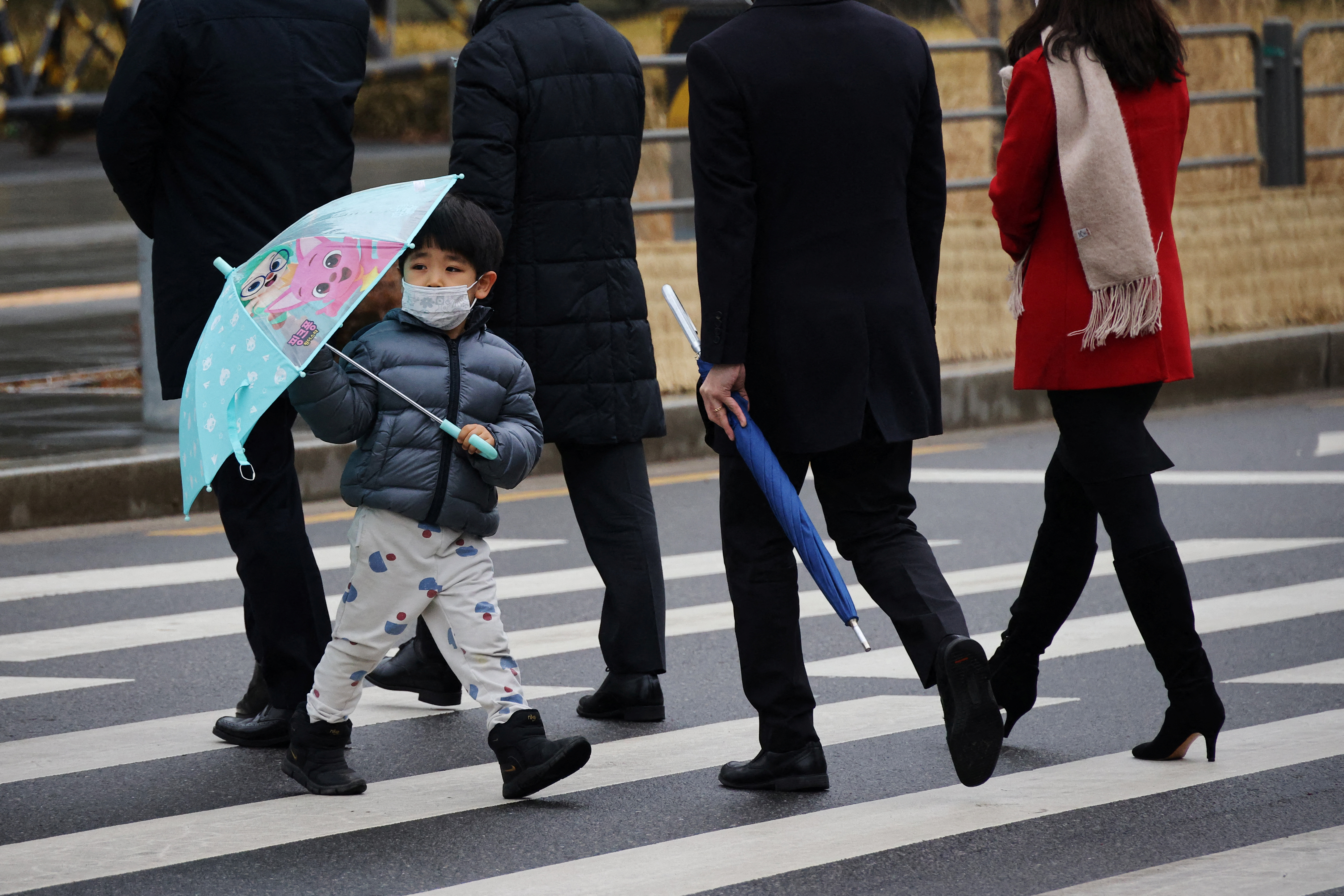 A boy wearing a mask to prevent contracting the coronavirus disease (COVID-19) walks on a zebra crossing in Seoul