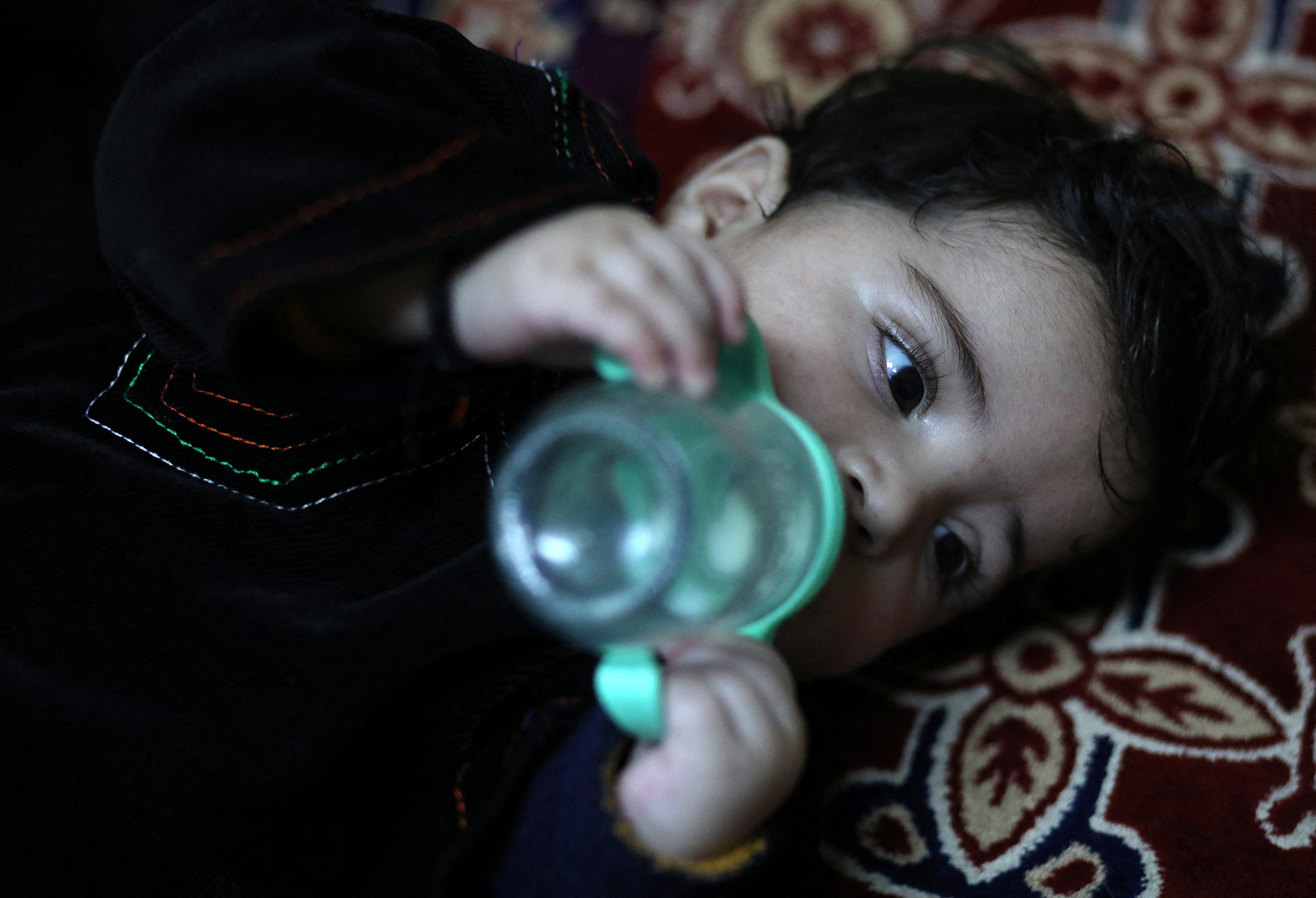 Baby Sohail Ahmadi drinks milk from a bottle inside the house of Hamid Safi in Kabul