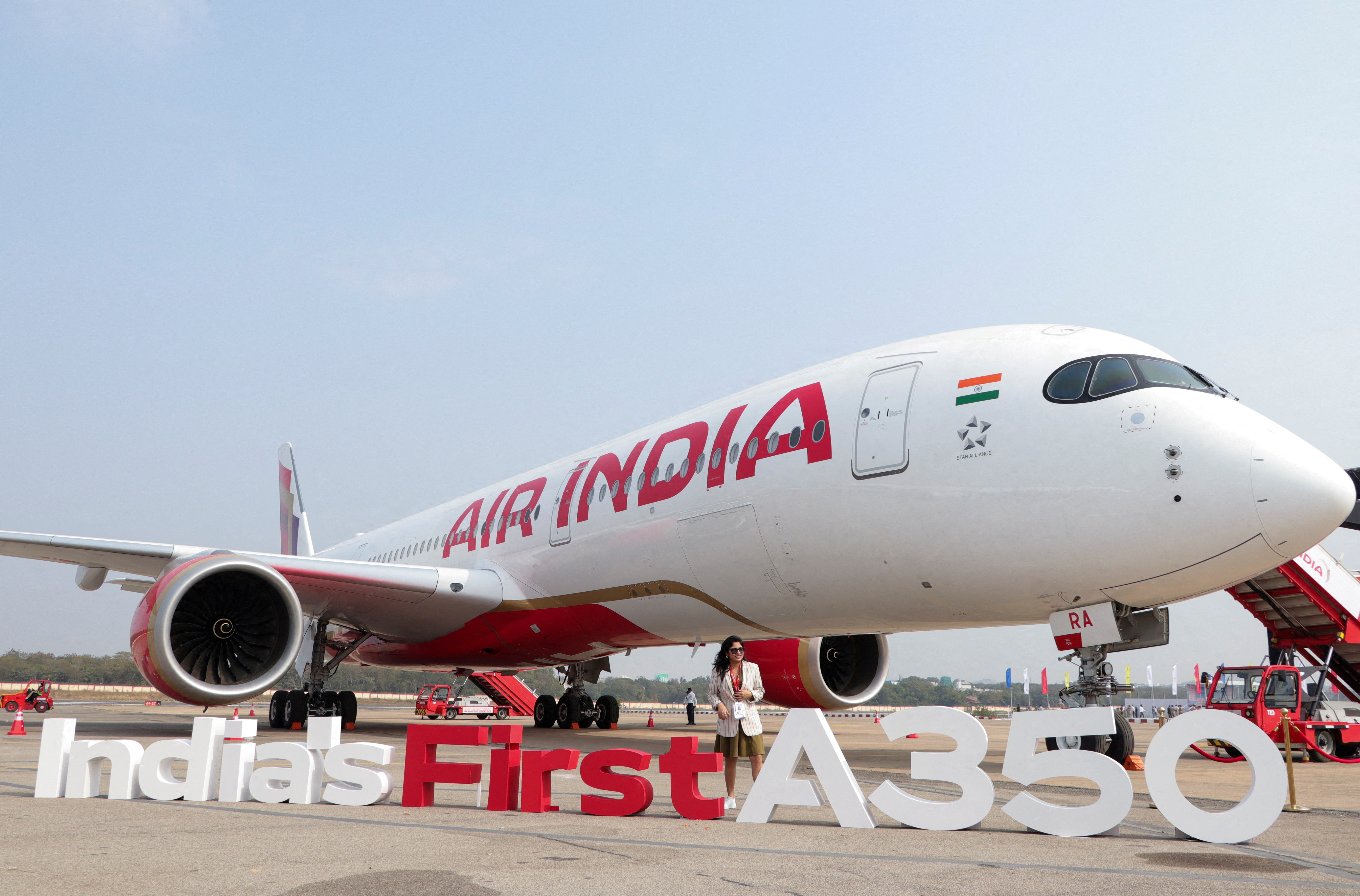 A woman stands next to the Air India Airbus A350 aeroplane, displayed at Wings India 2024 aviation event at Begumpet airport, Hyderabad