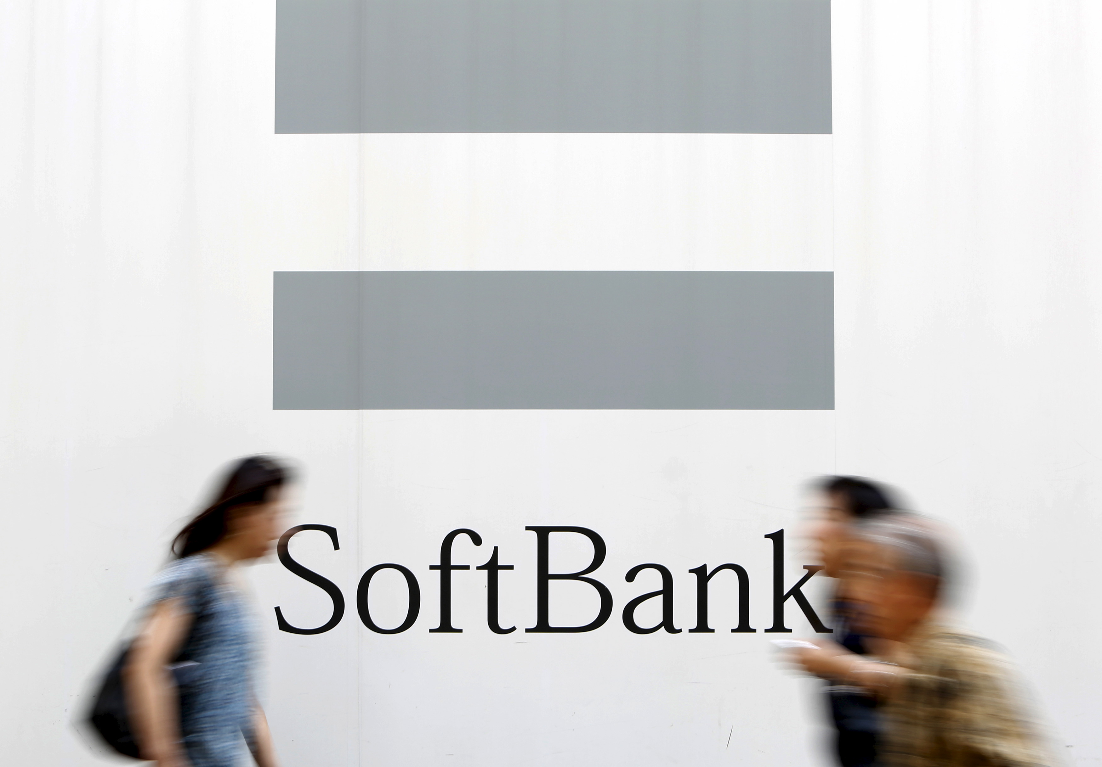 People walks past a logo of SoftBank Corp on a street in Tokyo