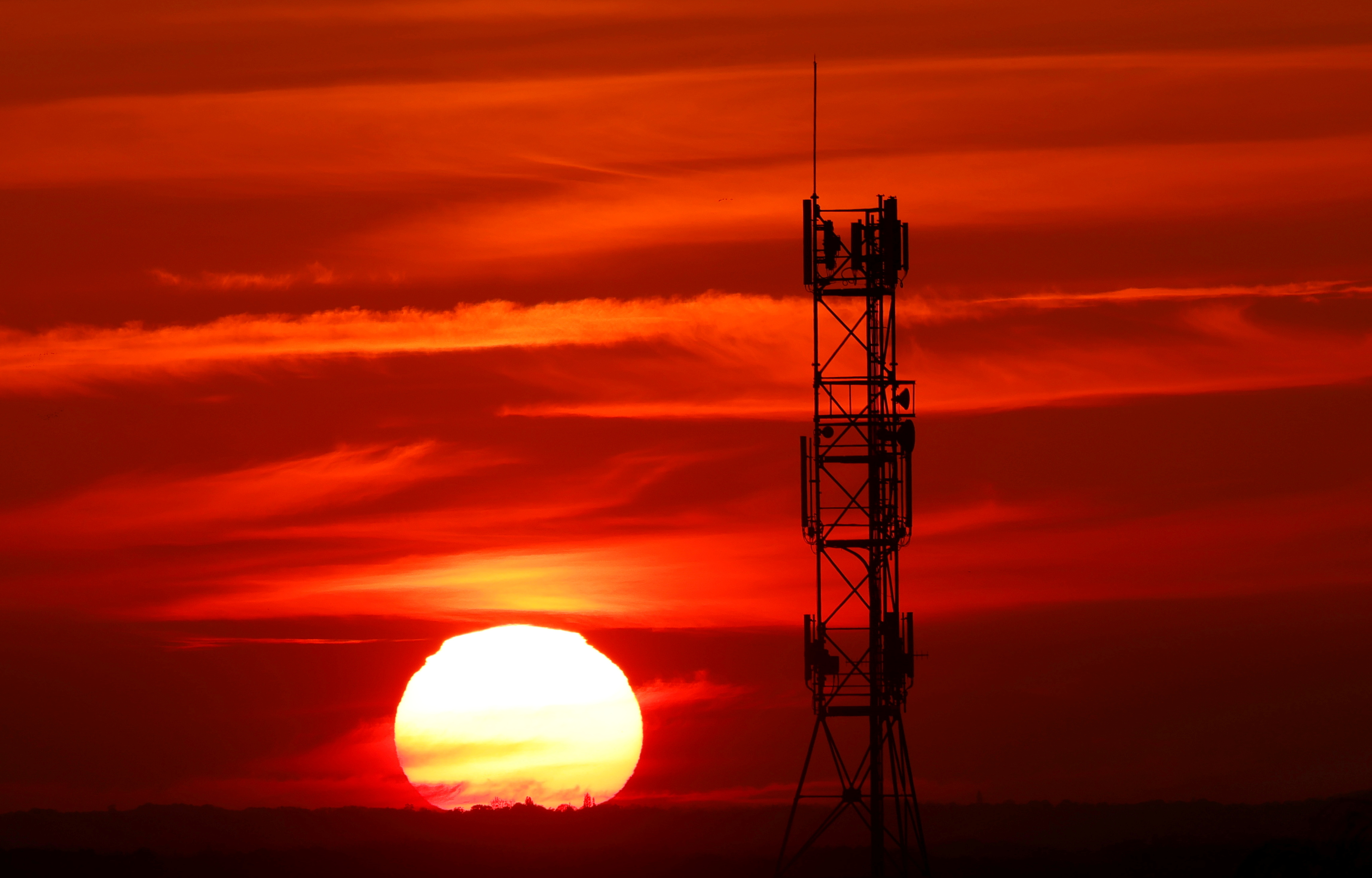 The sun sets behind transmitting antennas on a mobile-phone network relay mast in Vertou