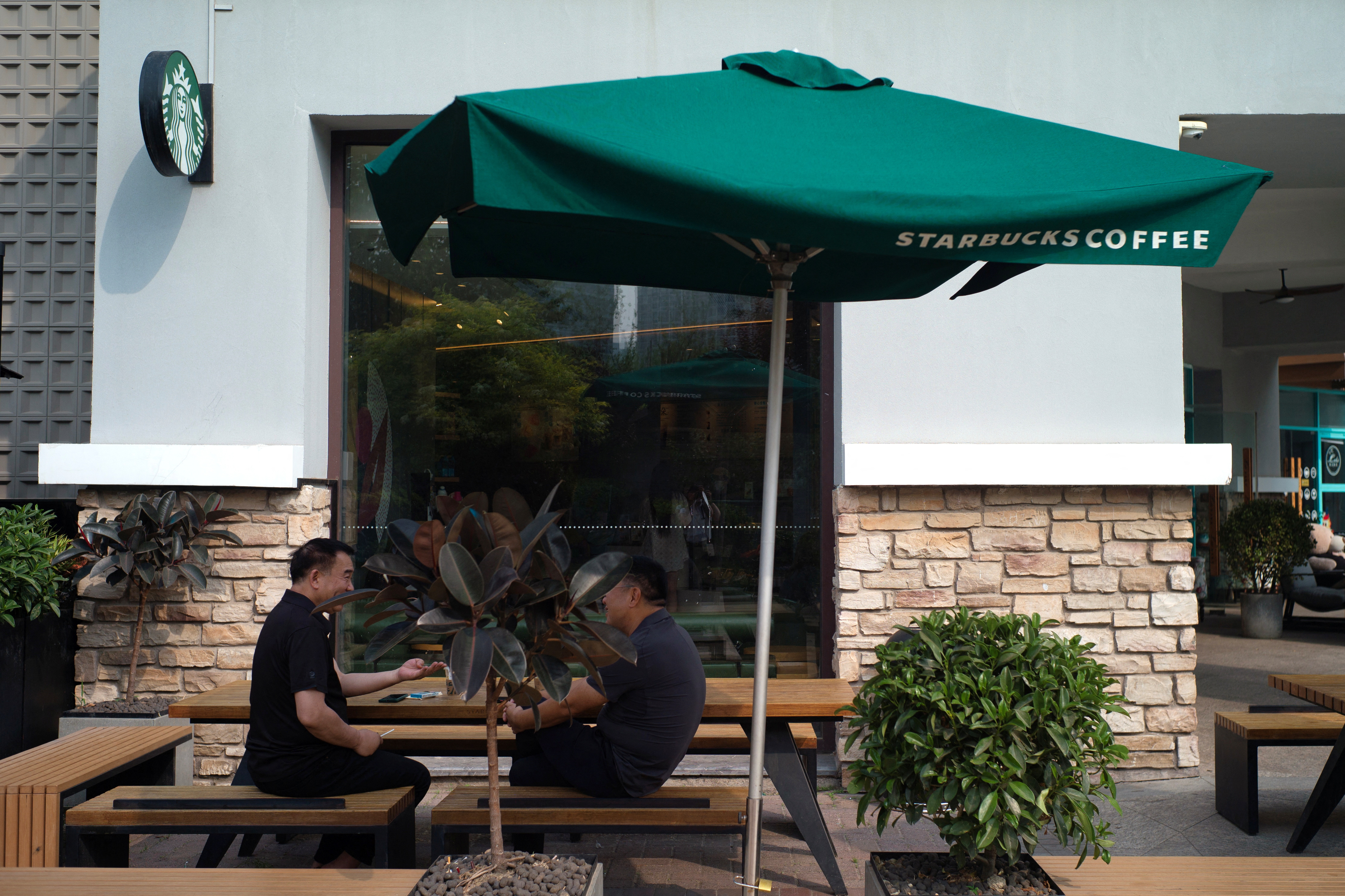 People sit outside a Starbucks coffee shop in Beijing