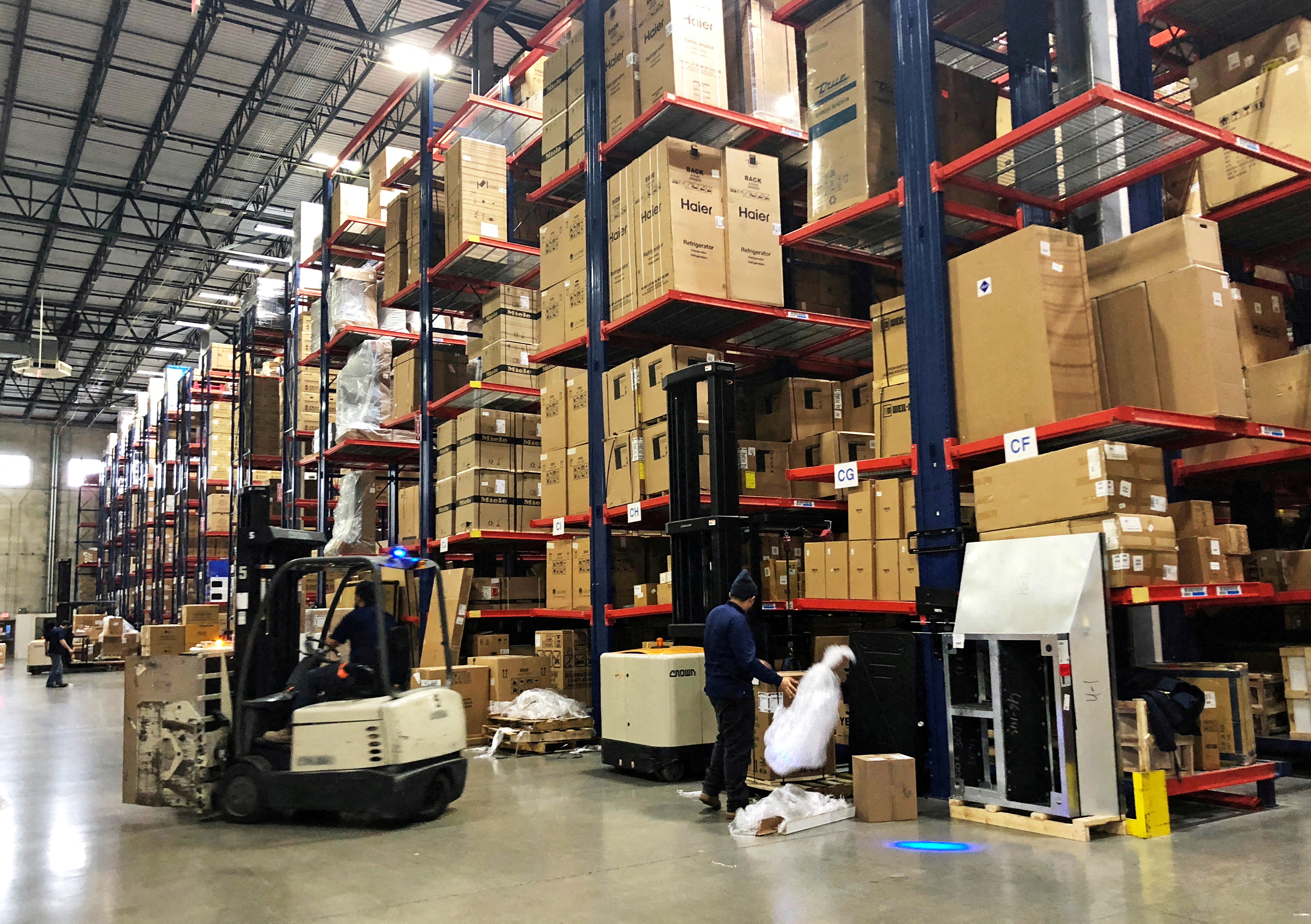Warehouse workers deal with inventory stacked up to the ceiling at an ABT Electronics Facility in Glenview