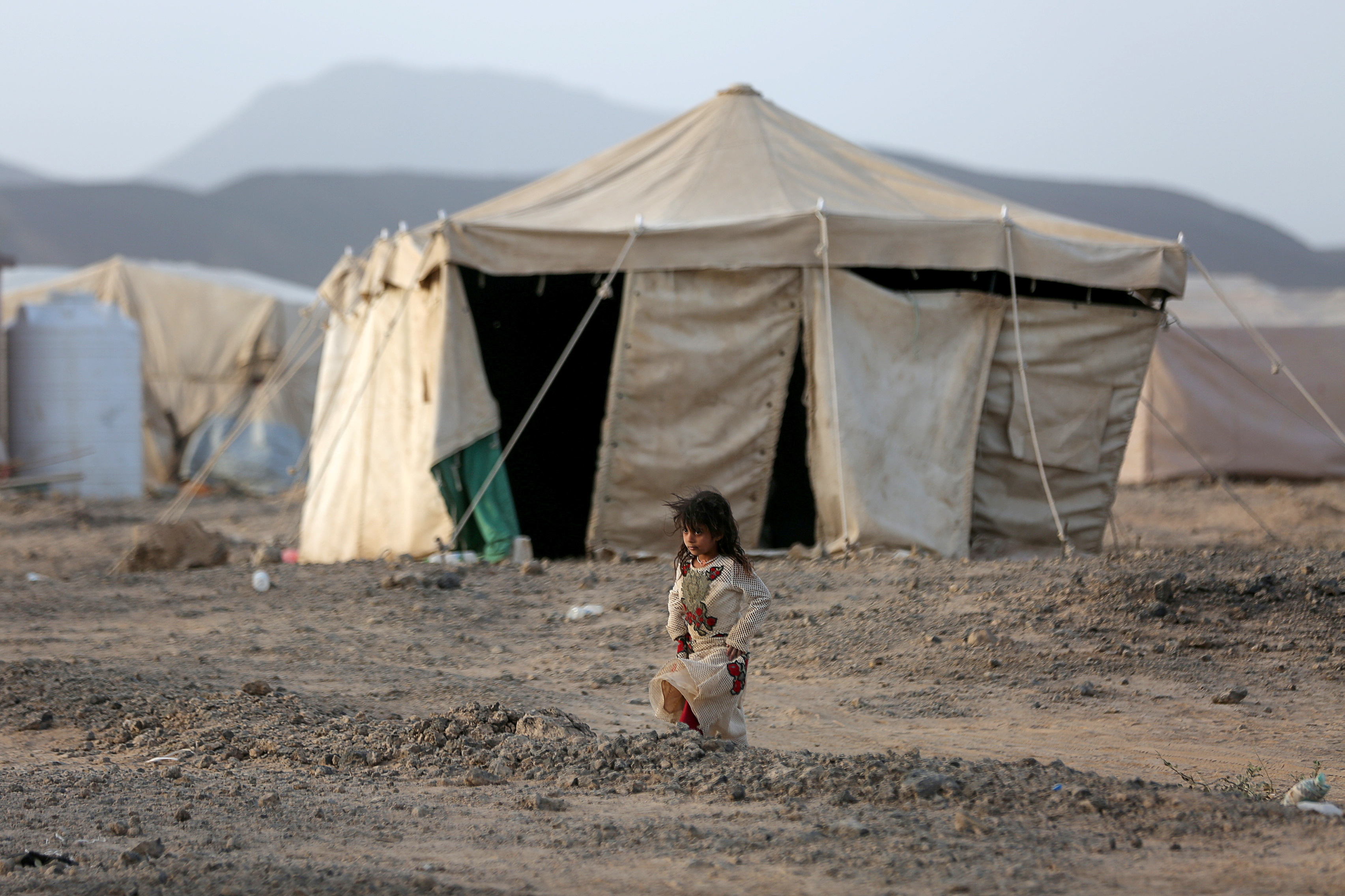 Girl walks past a tent at a camp for internally displaced people (IDPs) in Marib
